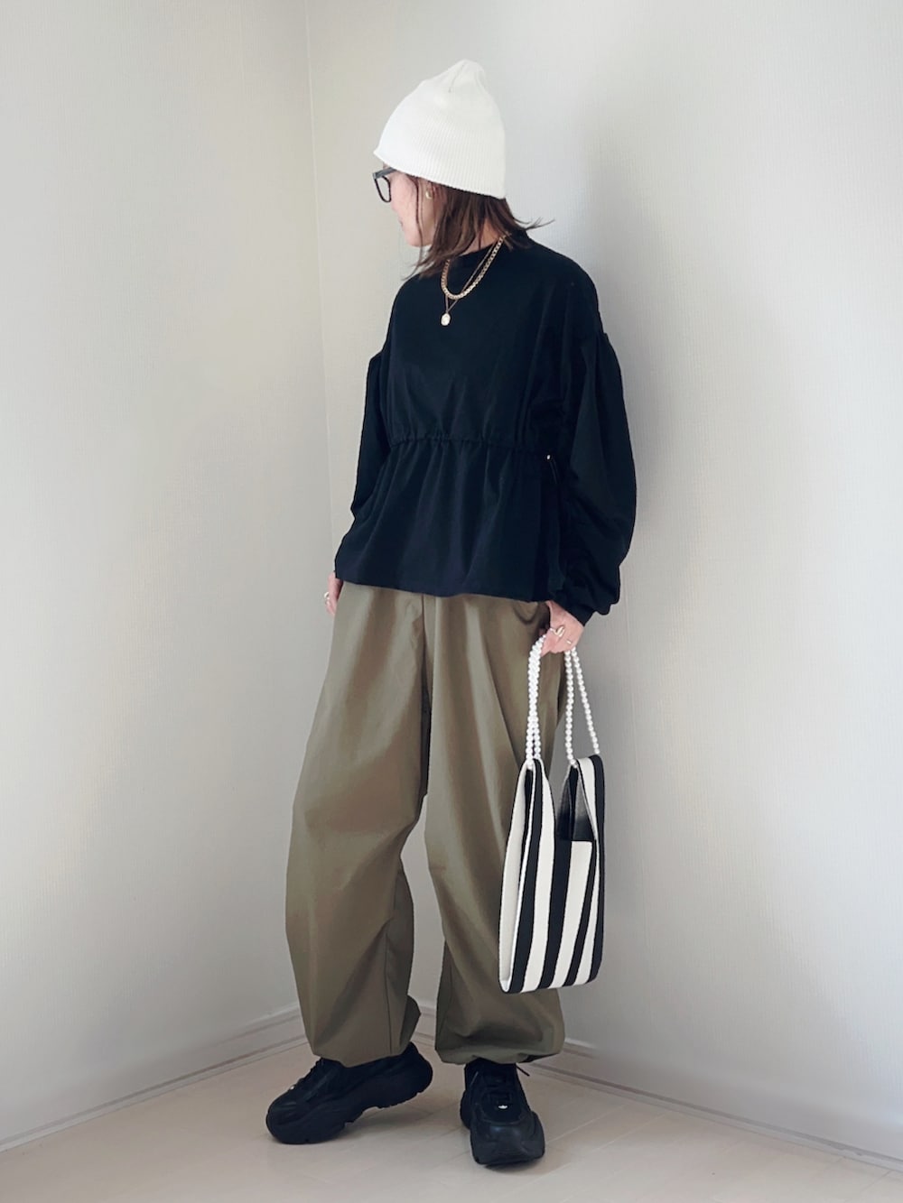 ブラック系のTシャツ/カットソー、グリーン系のその他パンツ、ホワイト系のショルダーバッグを着用したレディースの春コーディネートの2枚目の写真