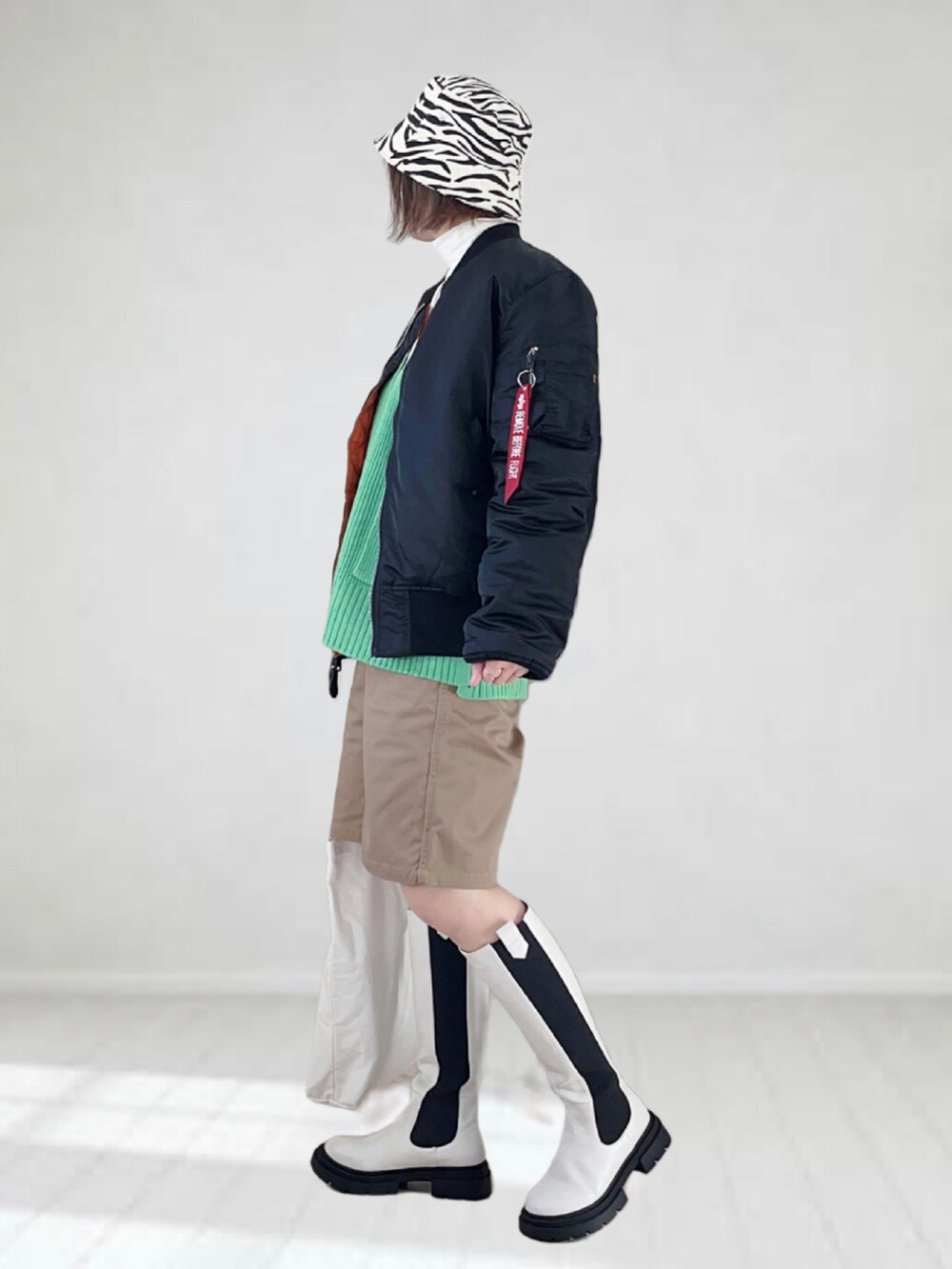 ブラック系のMA-1、ホワイト系のTシャツ/カットソー、グリーン系のカーディガン/ボレロを着用したレディースの冬コーディネートの4枚目の写真