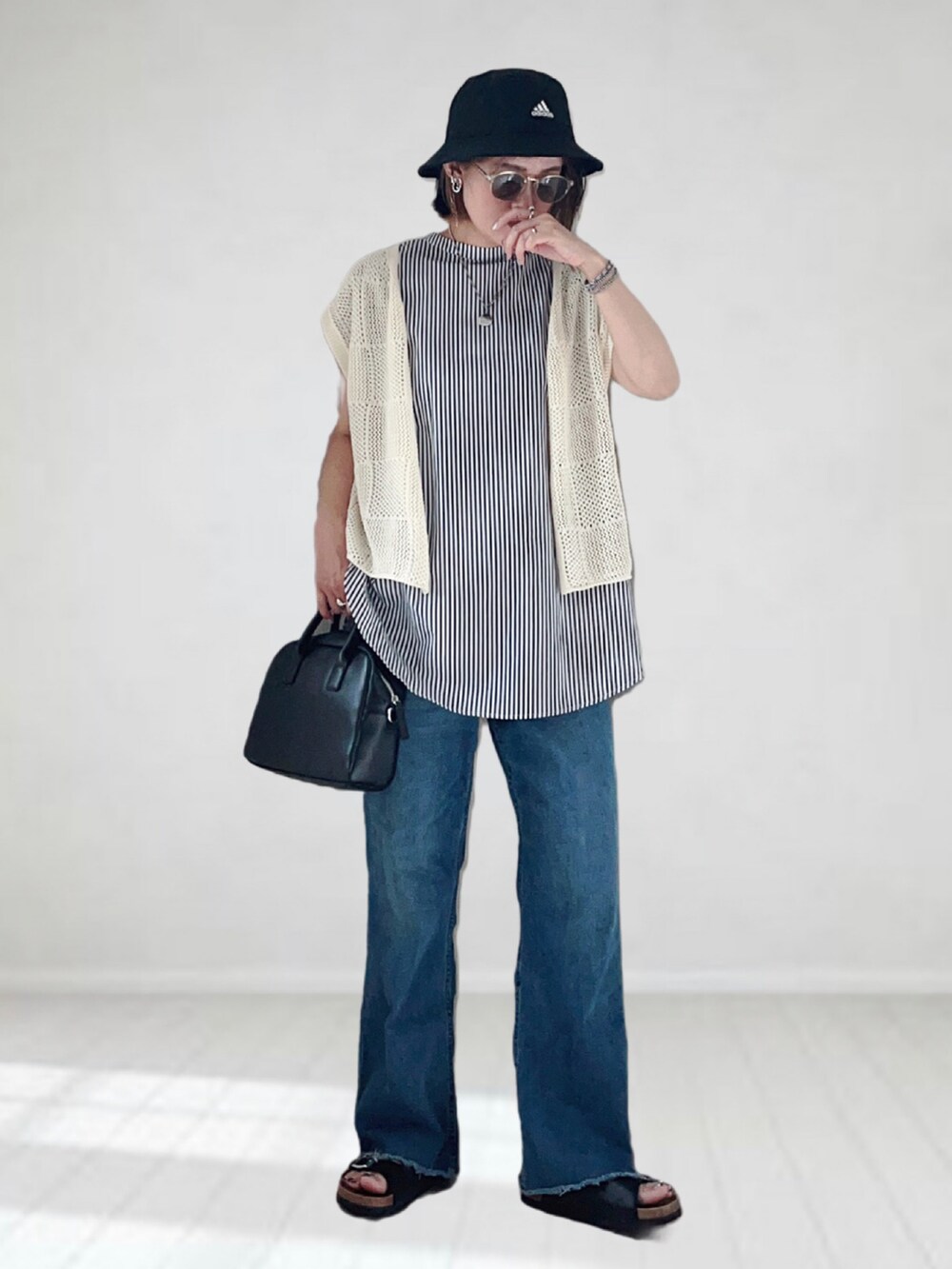 ブラック系のシャツ/ブラウス、ホワイト系のニット/セーター、ブルー系のデニムパンツを着用したレディースの夏コーディネートの2枚目の写真