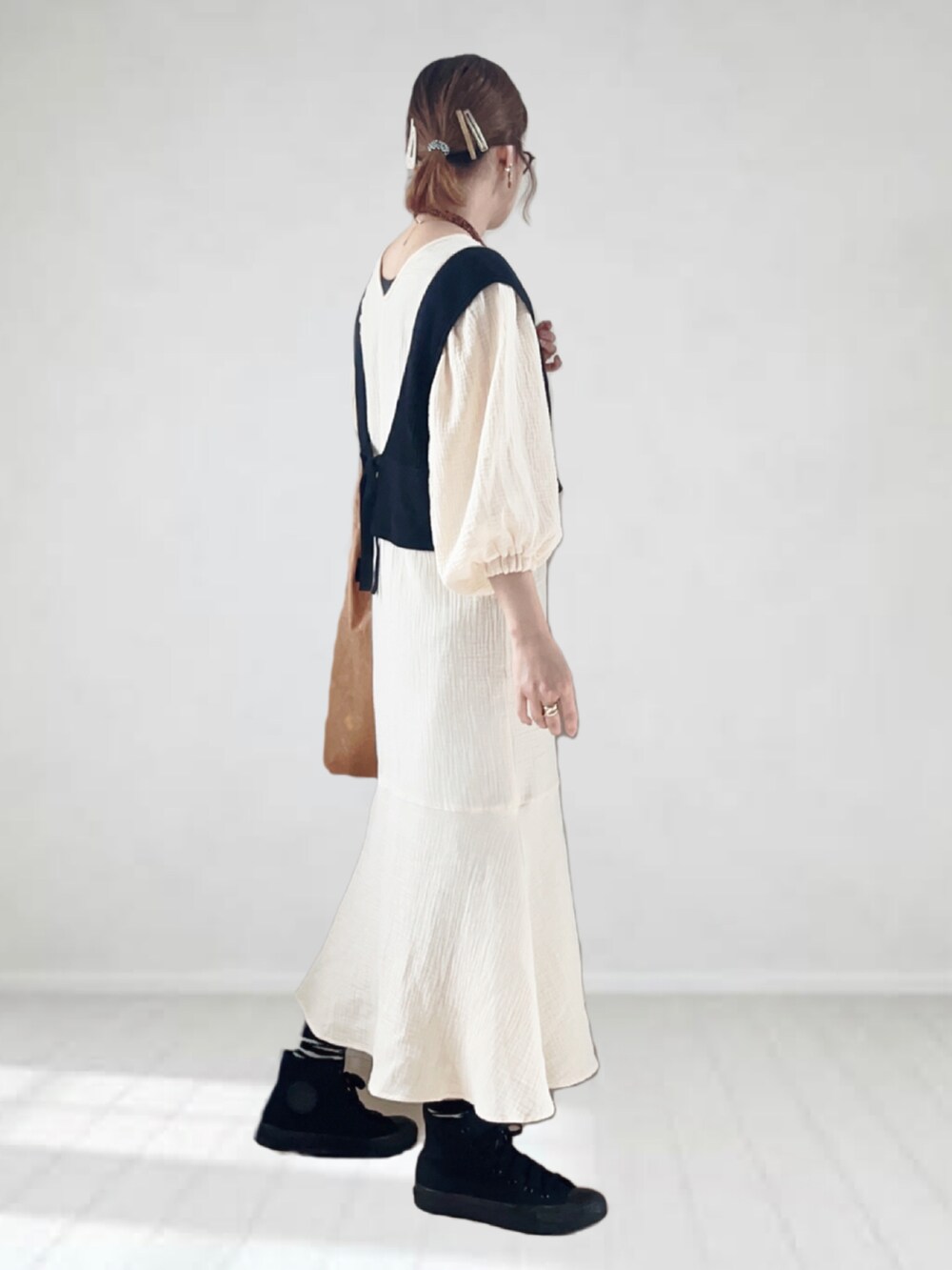 ホワイト系のワンピース、ブラック系のベスト、ベージュ系のトートバッグを着用したレディースの春コーディネートの3枚目の写真