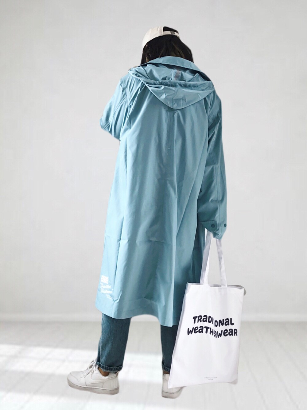 ホワイト系のニット/セーター、ブルー系のデニムパンツ、ホワイト系のトートバッグを着用したレディースの春コーディネートの4枚目の写真