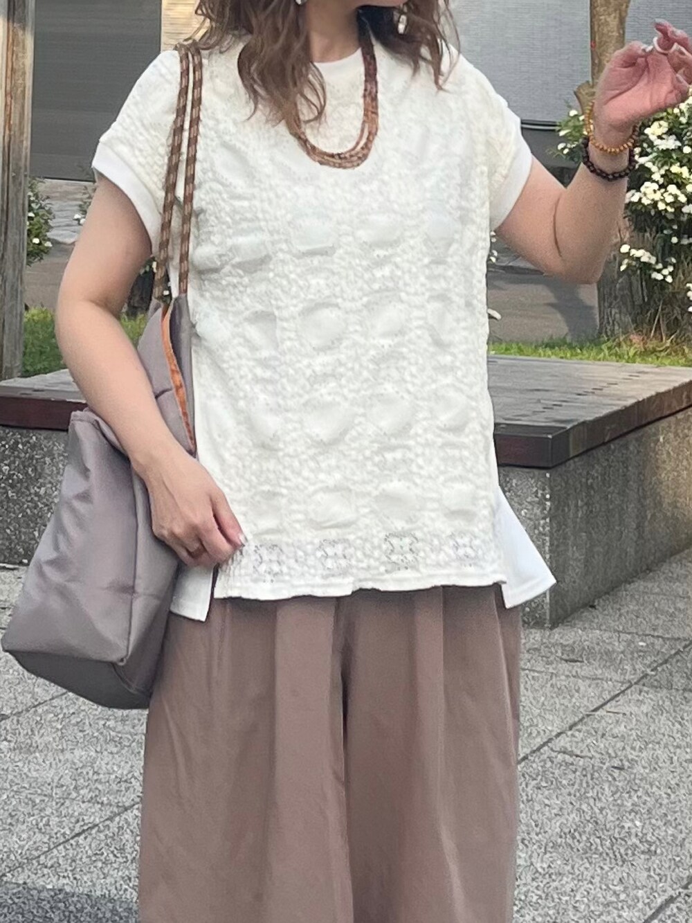 グレー系のトートバッグ、ホワイト系のTシャツ/カットソー、オレンジ系のスニーカーを着用したレディースの夏コーディネートの3枚目の写真