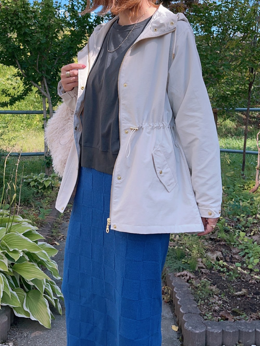 ベージュ系のマウンテンパーカー、グレー系のTシャツ/カットソー、ブルー系のスカートを着用したレディースの秋コーディネートの5枚目の写真