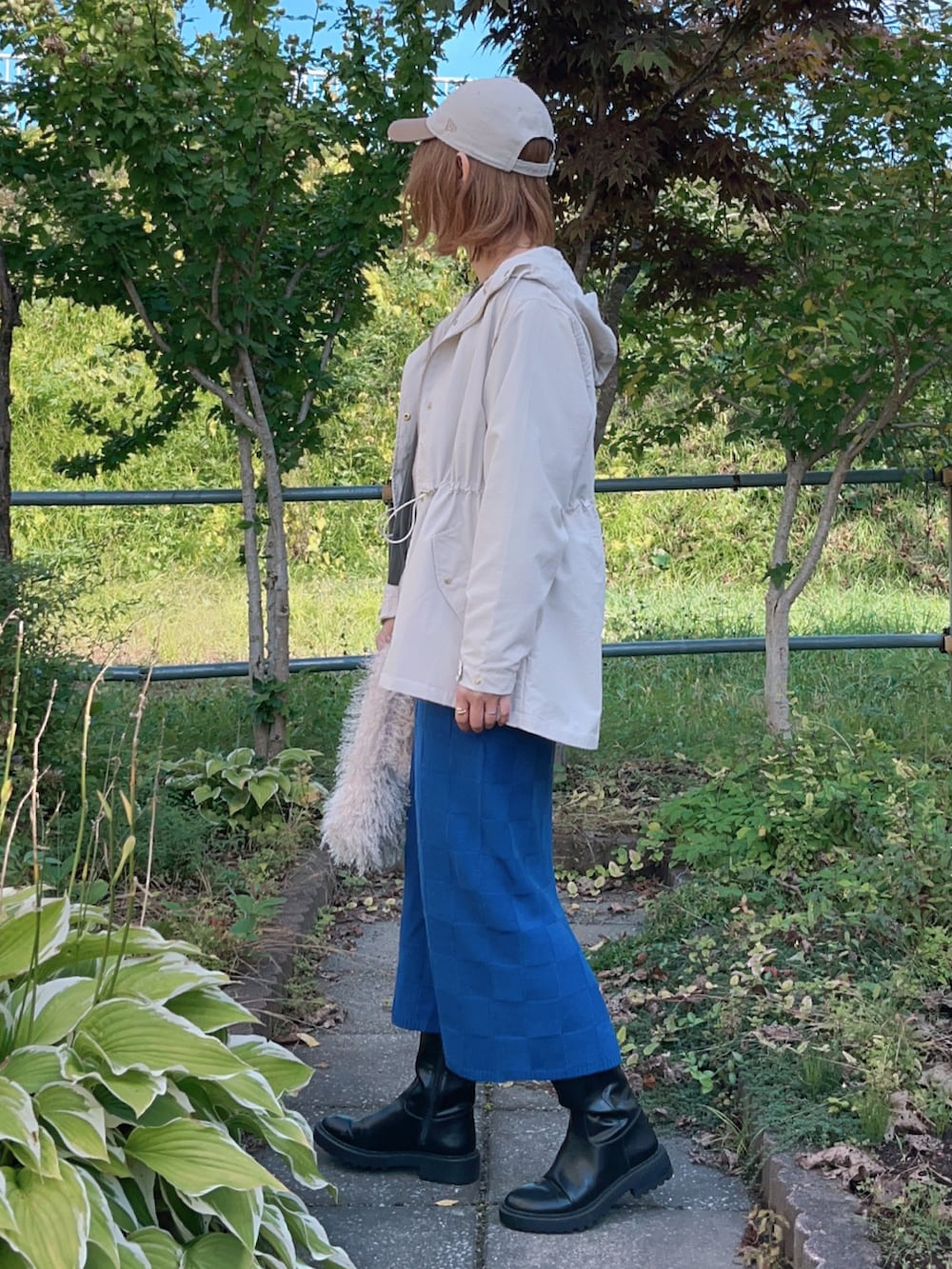 ベージュ系のマウンテンパーカー、グレー系のTシャツ/カットソー、ブルー系のスカートを着用したレディースの秋コーディネートの3枚目の写真