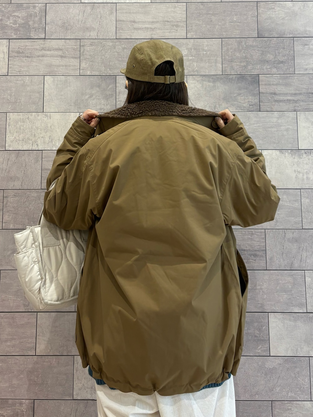 ベージュ系のミリタリージャケット、ブルー系のニット/セーター、ホワイト系のその他パンツを着用したレディースの冬コーディネートの3枚目の写真