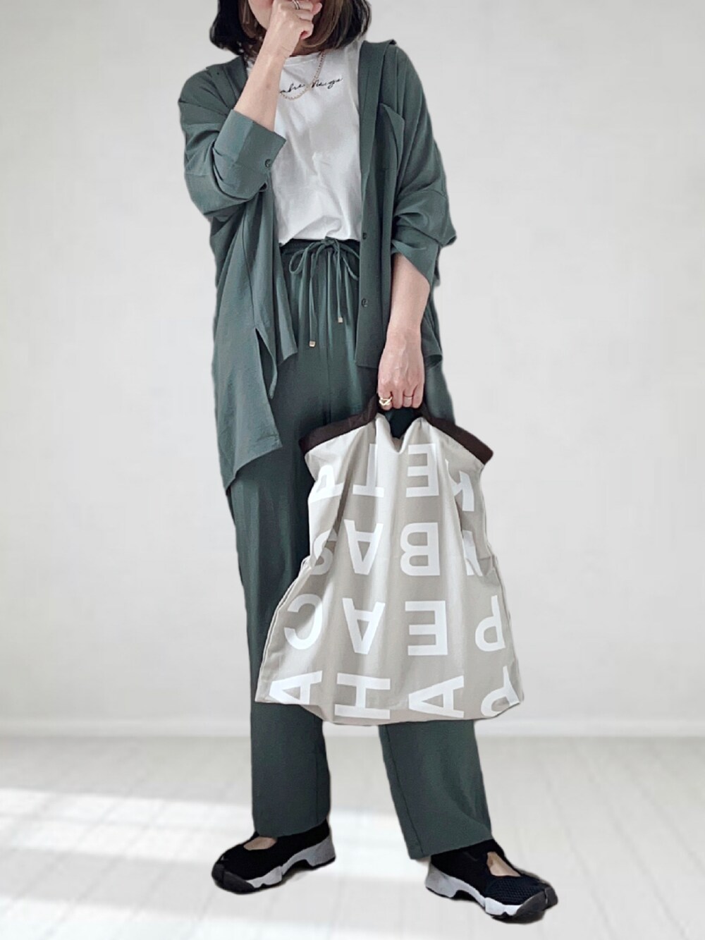 グレー系のトートバッグ、グリーン系のシャツ/ブラウス、ホワイト系のTシャツ/カットソーを着用したレディースの夏コーディネートの3枚目の写真