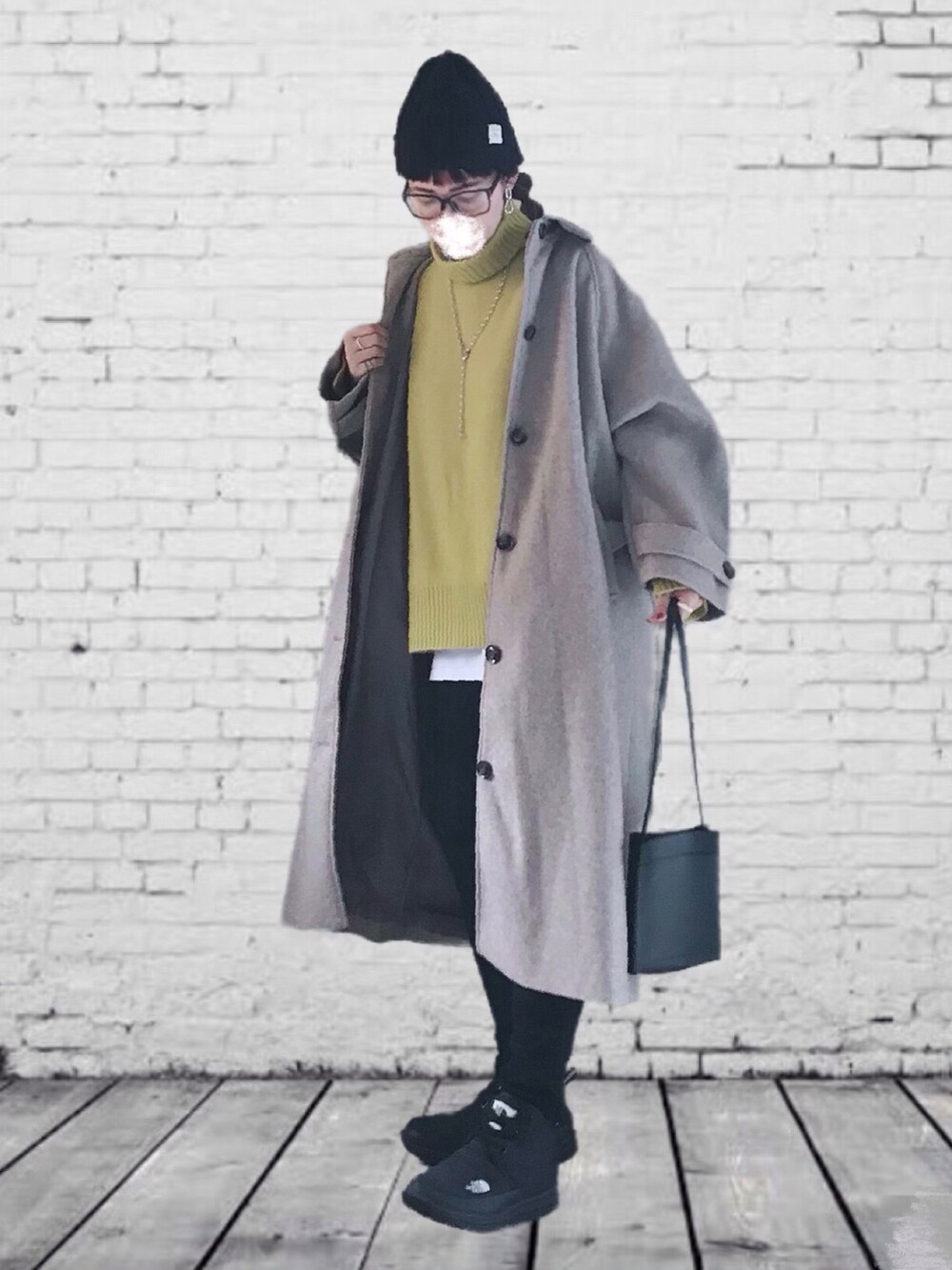 ベージュ系のステンカラーコート、イエロー系のニット/セーター、ホワイト系のTシャツ/カットソーを着用したレディースの秋コーディネートの2枚目の写真