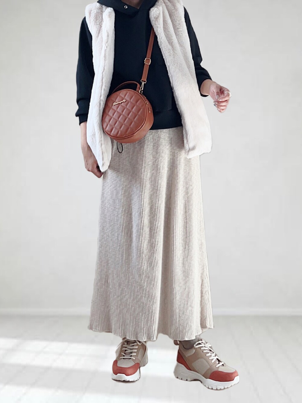 ベージュ系のスニーカー、ブラック系のパーカー、ホワイト系のスカートを着用したレディースの秋コーディネートの3枚目の写真