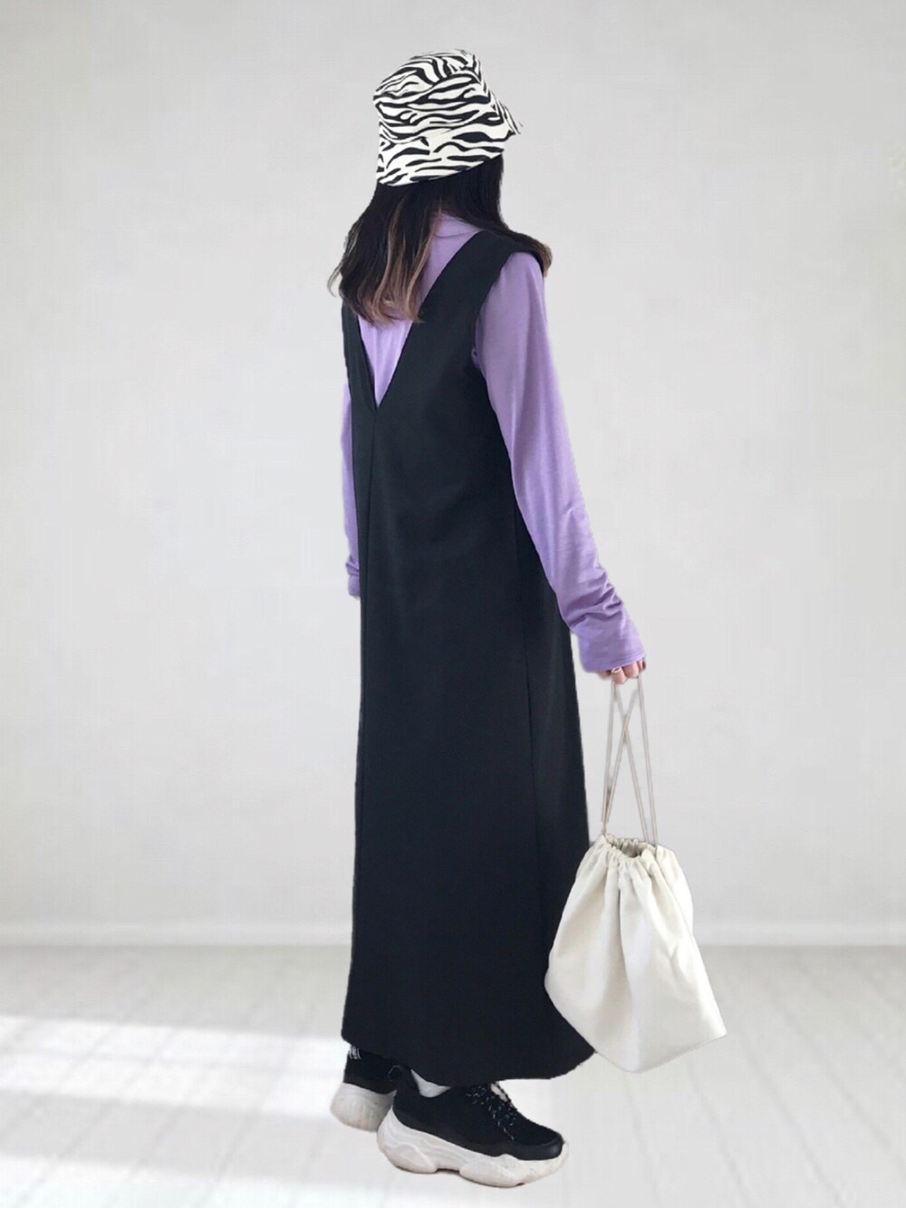 ブラック系のジャンパースカート、パープル系のTシャツ/カットソー、ホワイト系のショルダーバッグを着用したレディースの冬コーディネートの4枚目の写真