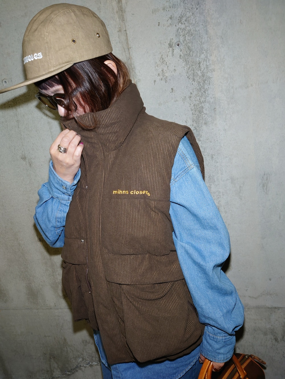 ブラウン系のダウンベスト、ブルー系のシャツ/ブラウス、ブラウン系のスニーカーを着用したレディースの秋コーディネートの4枚目の写真