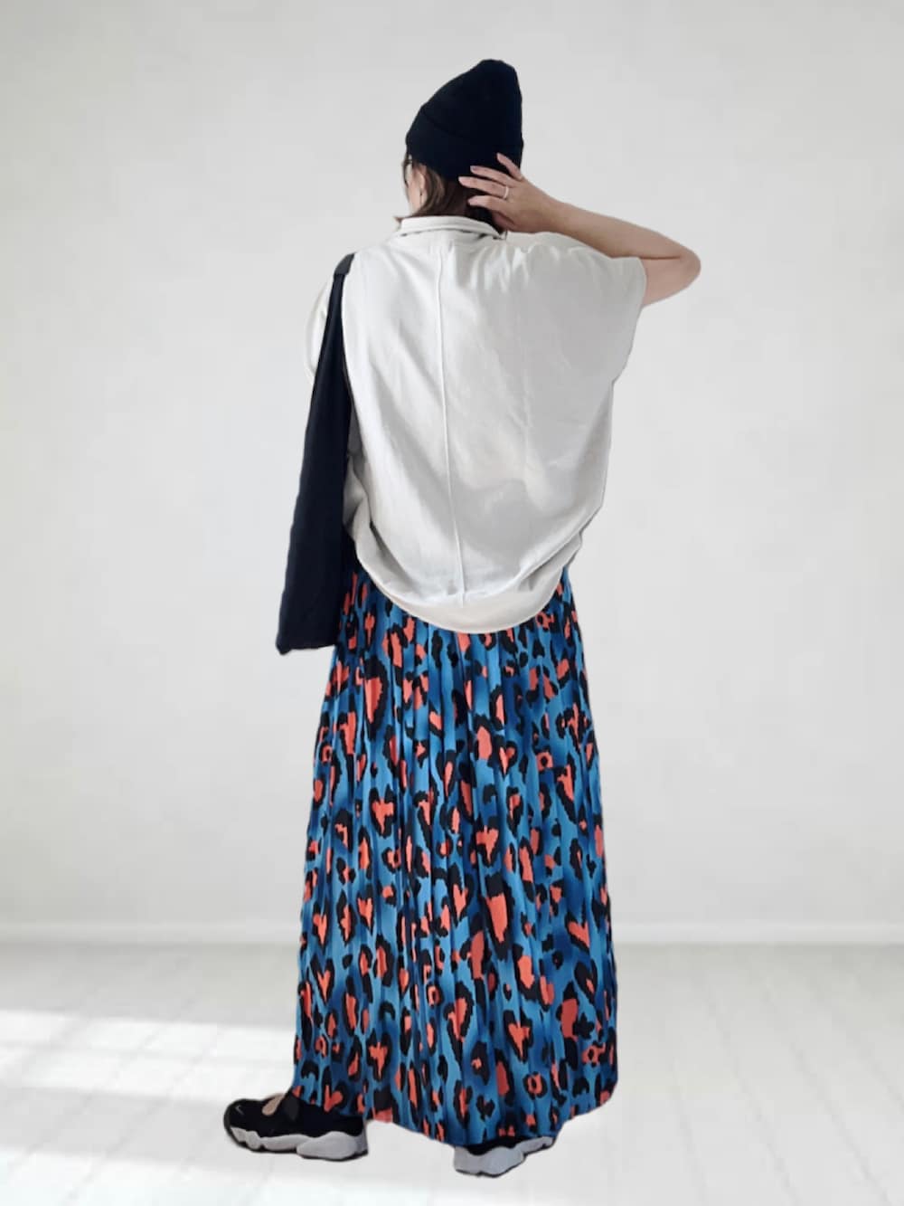 ブルー系のスカート、ベージュ系のTシャツ/カットソー、ブラック系のトートバッグを着用したレディースの夏コーディネートの3枚目の写真