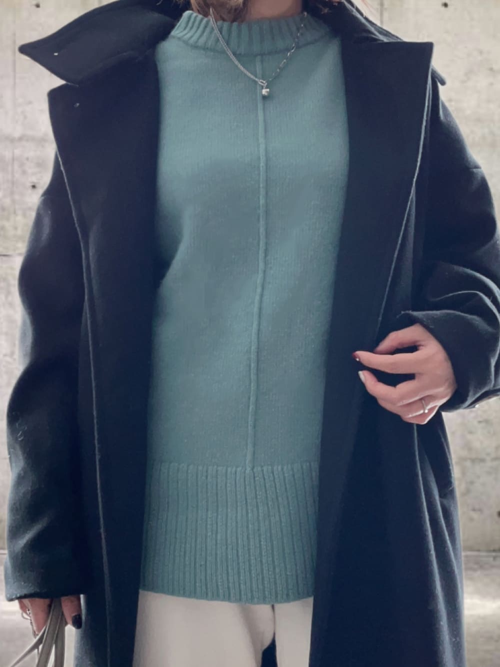 ブラック系のその他アウター、グリーン系のニット/セーター、ホワイト系のスウェットパンツを着用したレディースの冬コーディネートの3枚目の写真