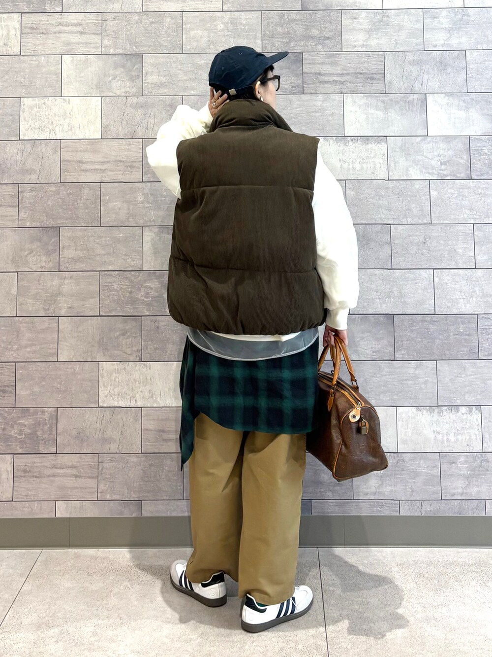 ブラウン系のダウンベスト、ホワイト系のスウェット、グリーン系のシャツ/ブラウスを着用したレディースの冬コーディネートの4枚目の写真