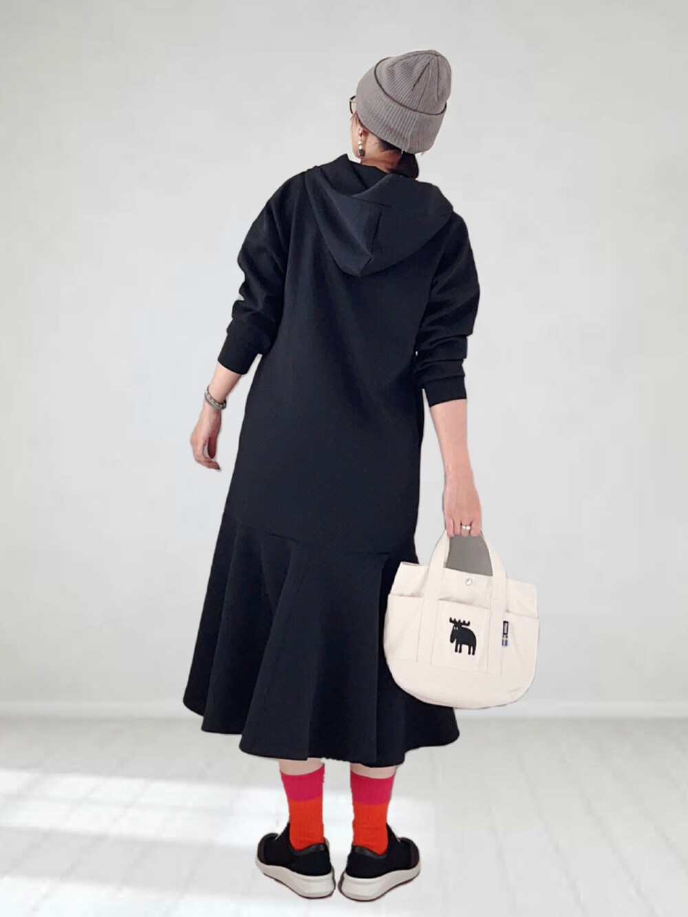 ブラック系のワンピース、ホワイト系のトートバッグ、ブラック系のスニーカーを着用したレディースの夏コーディネートの2枚目の写真