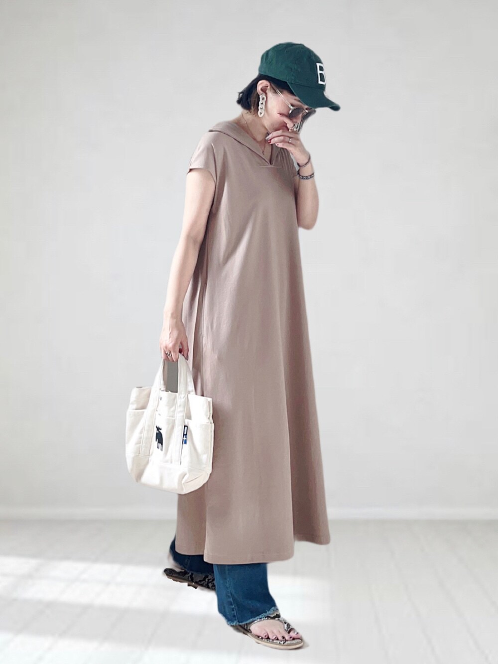 ベージュ系のワンピース、ブルー系のデニムパンツ、ホワイト系のトートバッグを着用したレディースの夏コーディネートの2枚目の写真