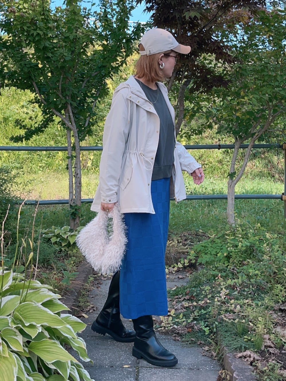 ベージュ系のマウンテンパーカー、グレー系のTシャツ/カットソー、ブルー系のスカートを着用したレディースの秋コーディネートの2枚目の写真