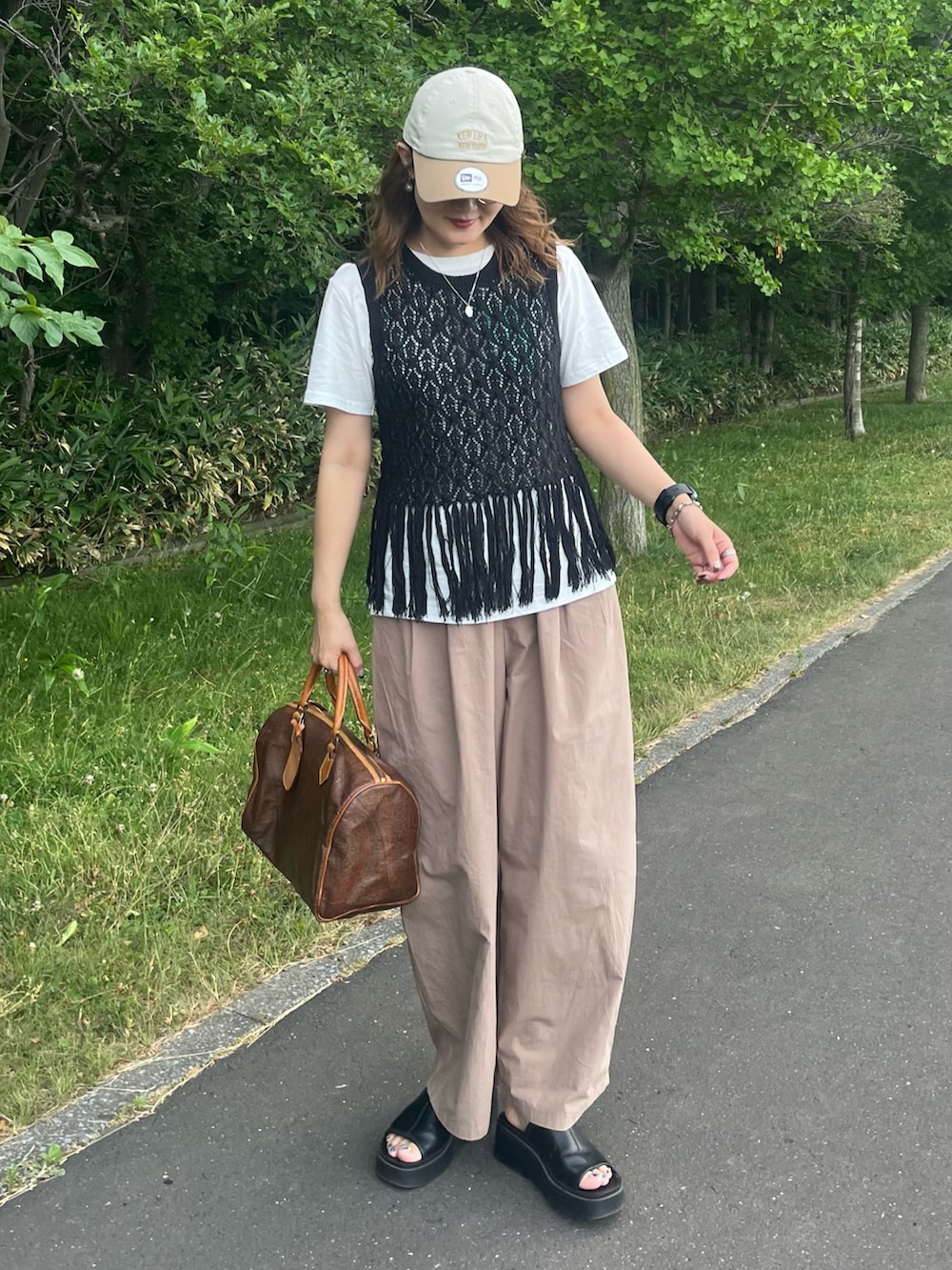 ブラック系のベスト、ブラウン系のスラックス、ホワイト系のTシャツ/カットソーを着用したレディースの夏コーディネートの2枚目の写真