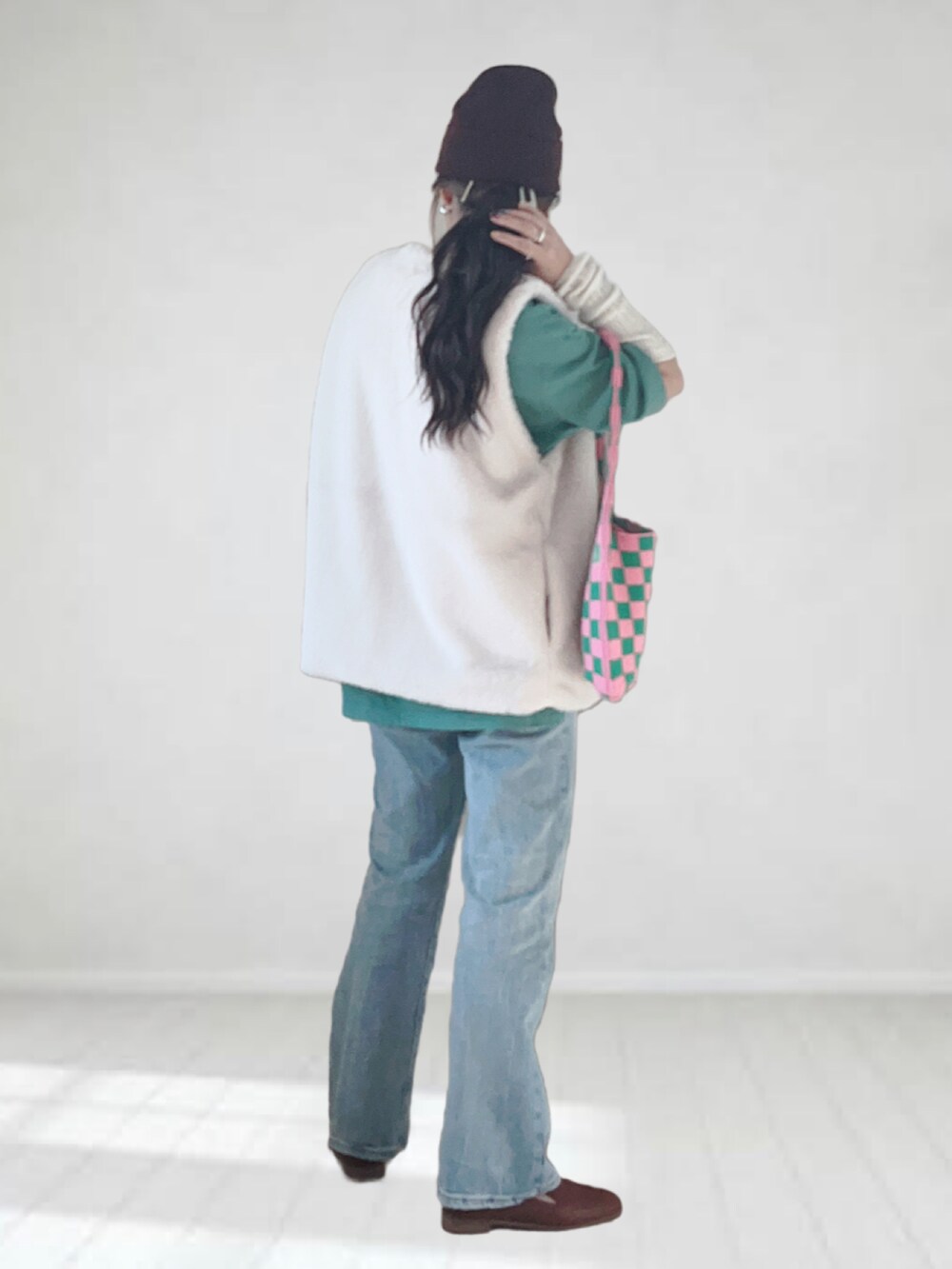 ブルー系のデニムパンツ、ホワイト系のベスト、グリーン系のTシャツ/カットソーを着用したレディースの秋コーディネートの2枚目の写真