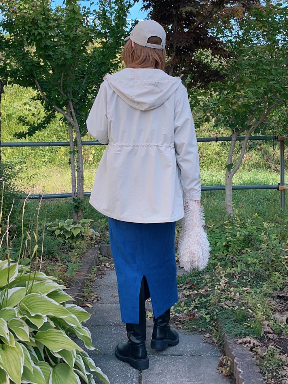 ベージュ系のマウンテンパーカー、グレー系のTシャツ/カットソー、ブルー系のスカートを着用したレディースの秋コーディネートの4枚目の写真