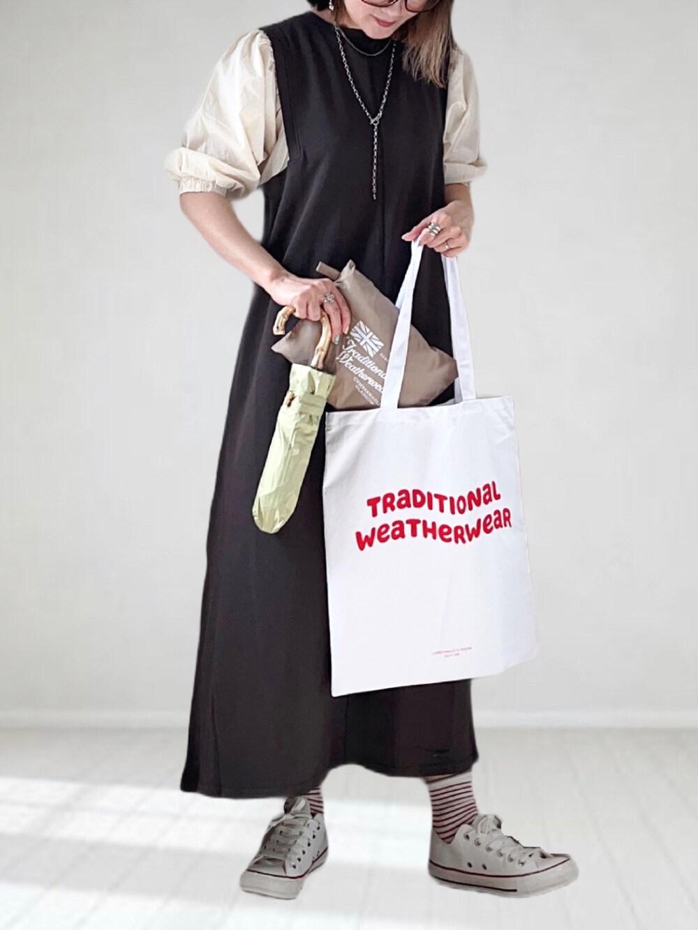 グレー系のワンピース、ホワイト系のスニーカー、ベージュ系のレインコート/ポンチョを着用したレディースの春コーディネートの3枚目の写真