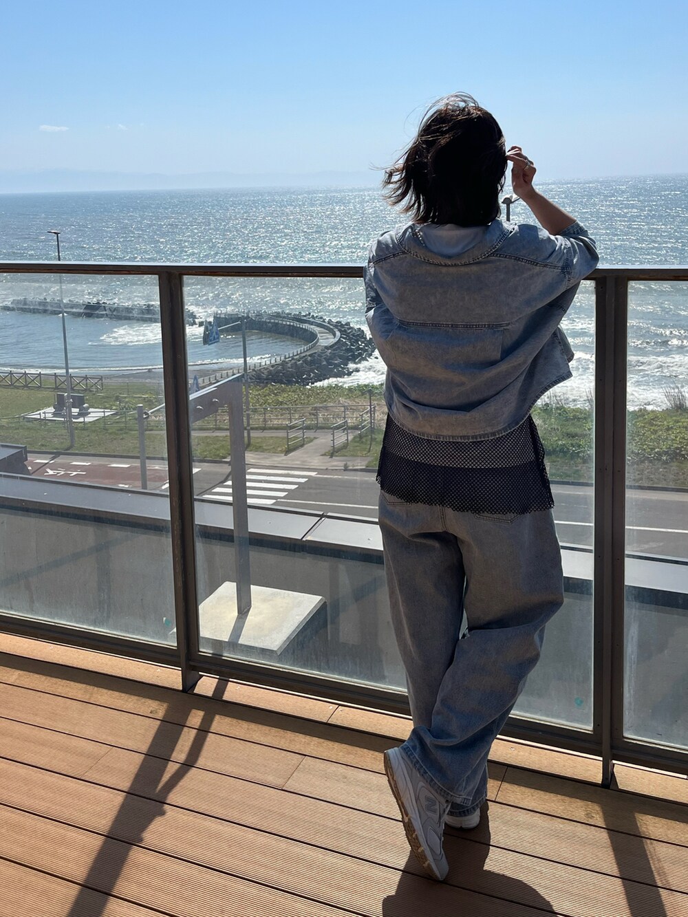 ブルー系のシャツ/ブラウス、ブルー系のデニムパンツ、ブラック系のワンピースを着用したレディースの春コーディネートの2枚目の写真