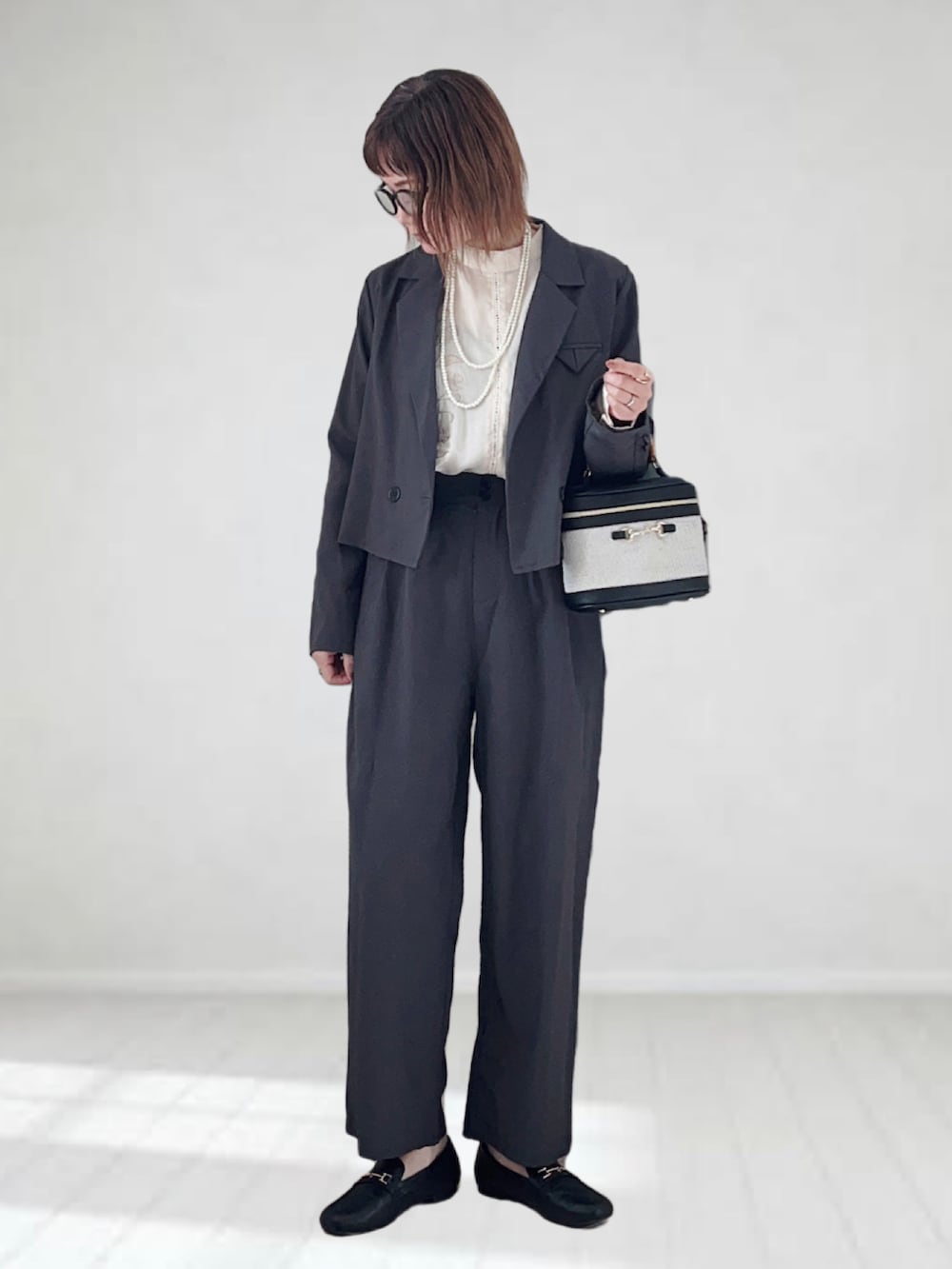 グレー系のテーラードジャケット、ホワイト系のシャツ/ブラウス、ホワイト系のハンドバッグを着用したレディースの冬コーディネートの2枚目の写真