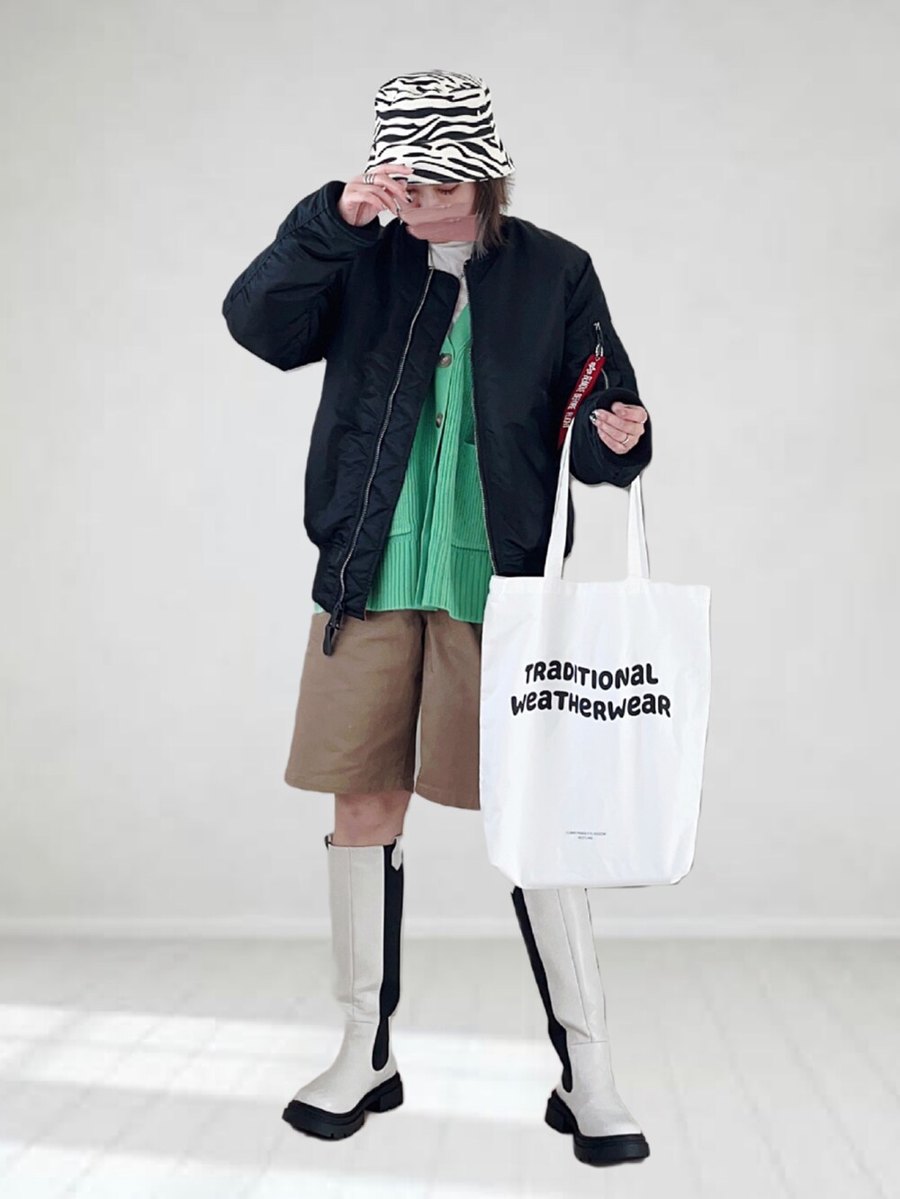 ブラック系のMA-1、ホワイト系のTシャツ/カットソー、グリーン系のカーディガン/ボレロを着用したレディースの冬コーディネートの2枚目の写真