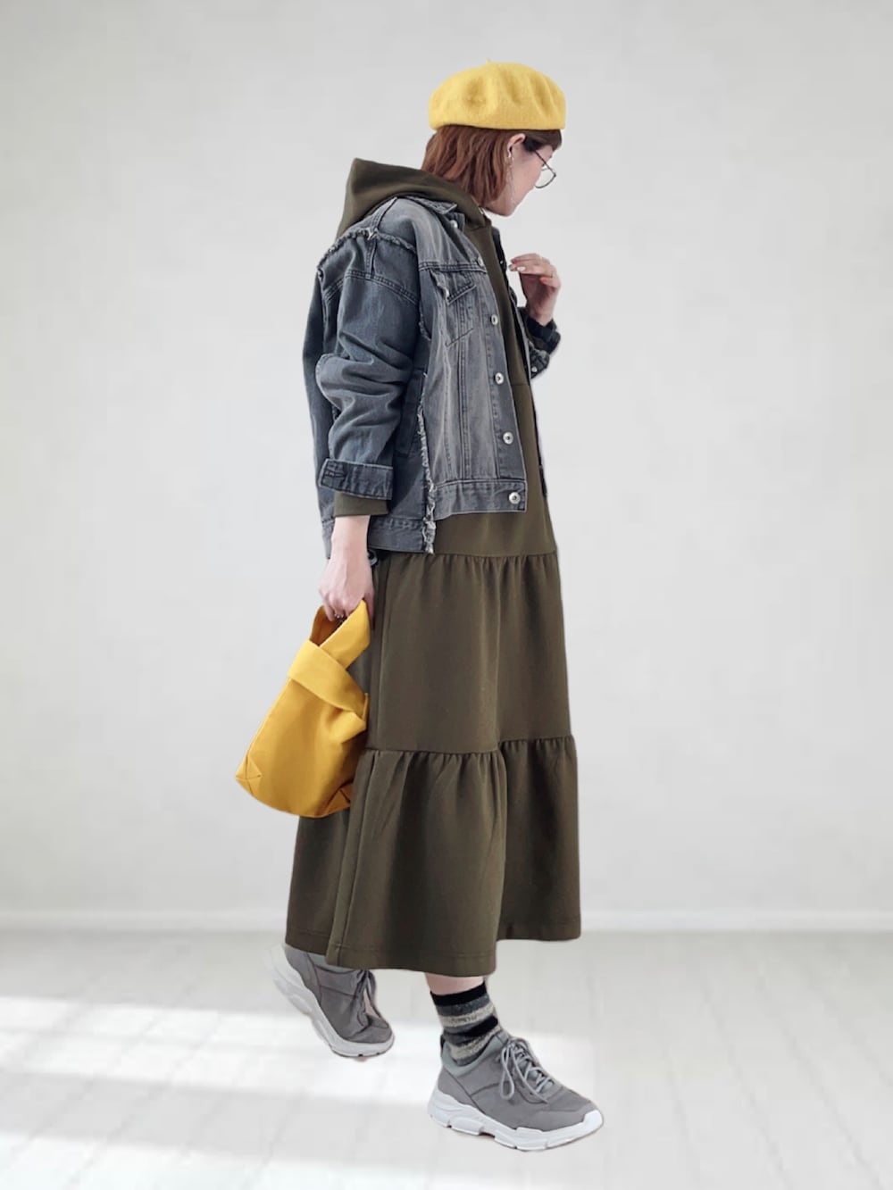 グリーン系のワンピース、ブラック系のデニムジャケット、イエロー系のトートバッグを着用したレディースの春コーディネートの2枚目の写真