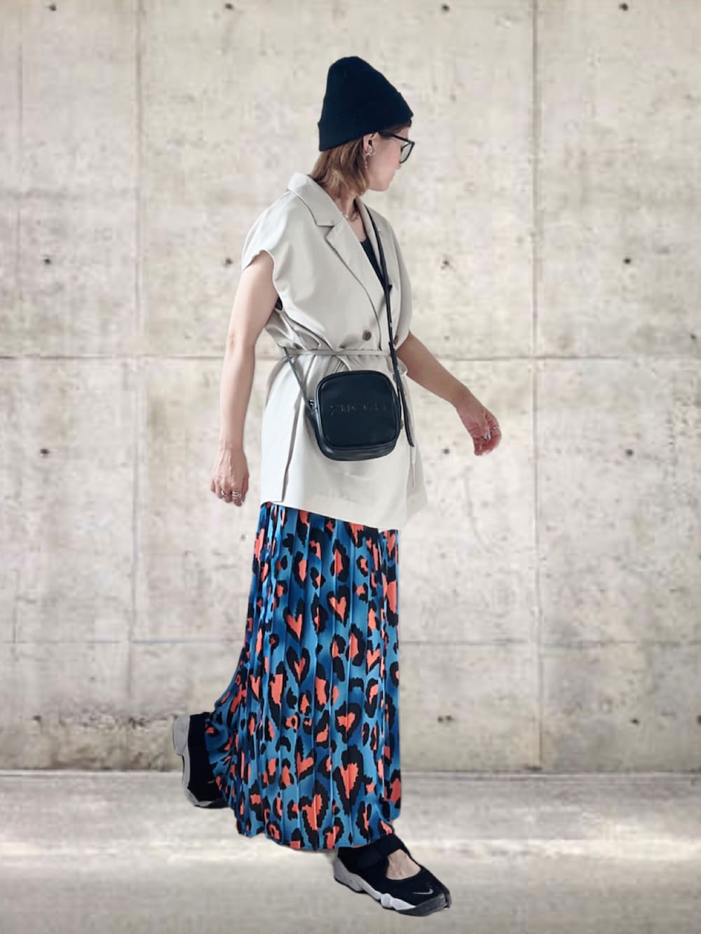 ホワイト系のベスト、ブルー系のスカート、ブラック系のショルダーバッグを着用したレディースの夏コーディネートの2枚目の写真