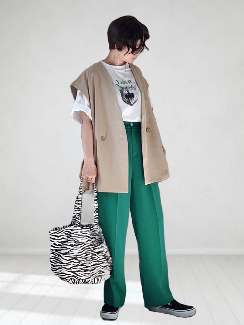 ベージュ系のベスト、ホワイト系のTシャツ/カットソー、グリーン系のスラックスを着用したレディースの春コーディネートの2枚目の写真