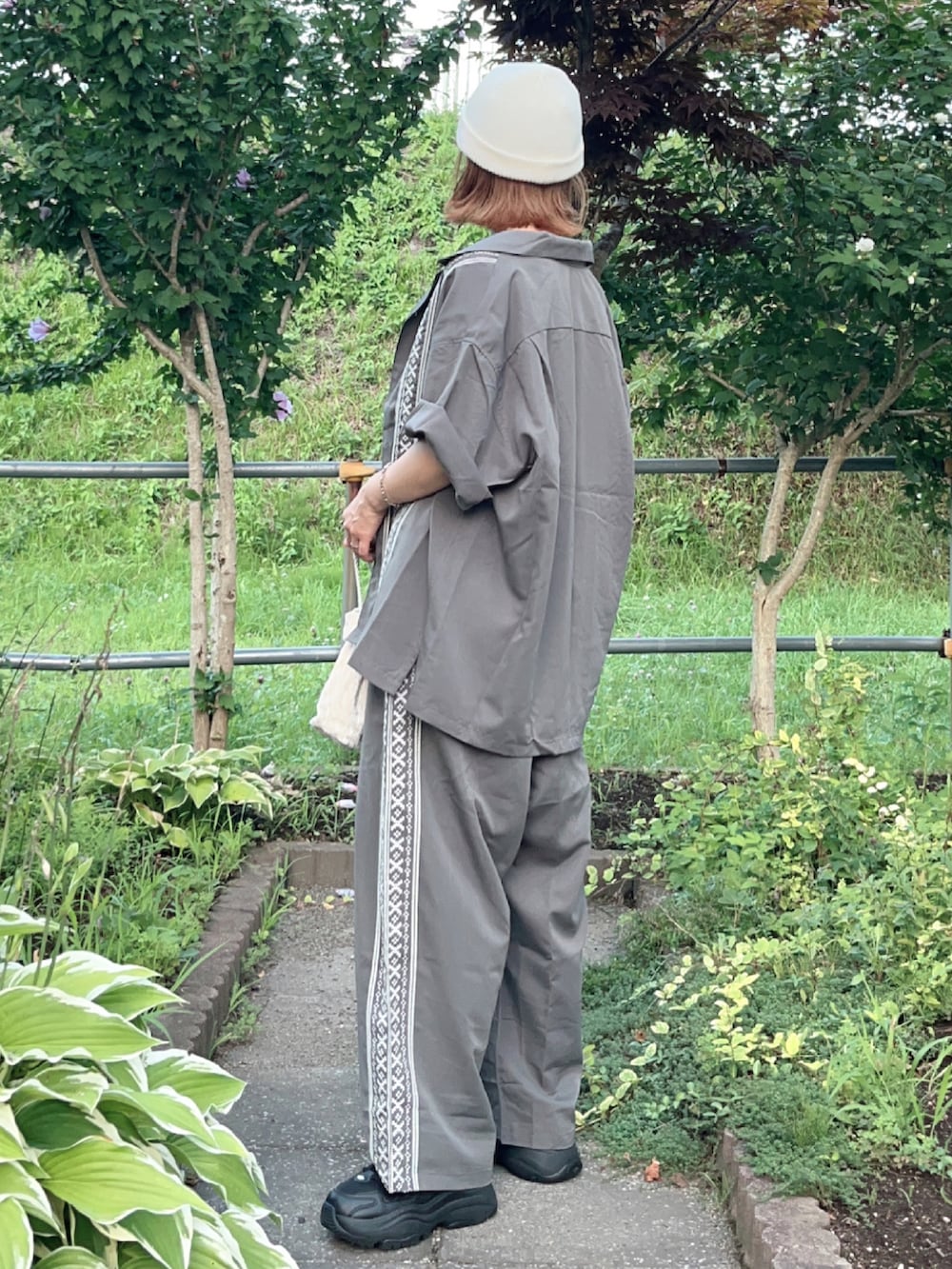 グレー系のシャツ/ブラウス、グレー系のその他パンツ、ブラック系のスニーカーを着用したレディースの夏コーディネートの5枚目の写真