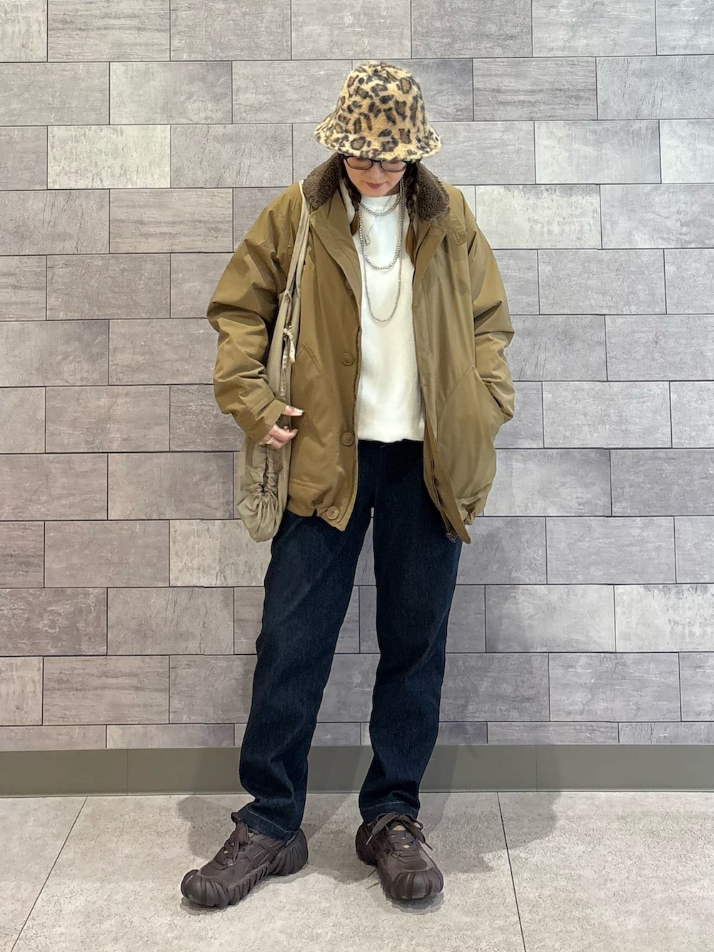 ベージュ系のミリタリージャケット、ホワイト系のスウェット、ブルー系のその他パンツを着用したレディースの春コーディネートの5枚目の写真