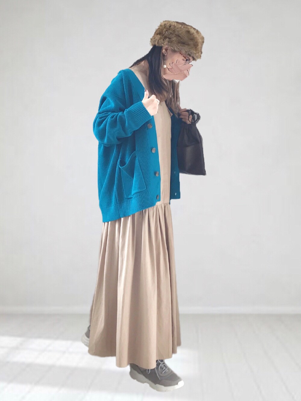 ブルー系のカーディガン/ボレロ、ベージュ系のワンピース、ブラウン系のハンドバッグを着用したレディースの冬コーディネートの2枚目の写真
