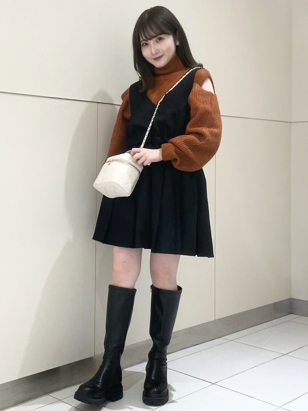 ブラック系のブーツ、ブラック系のワンピース、オレンジ系のニット/セーターを着用したレディースの秋コーディネートの5枚目の写真