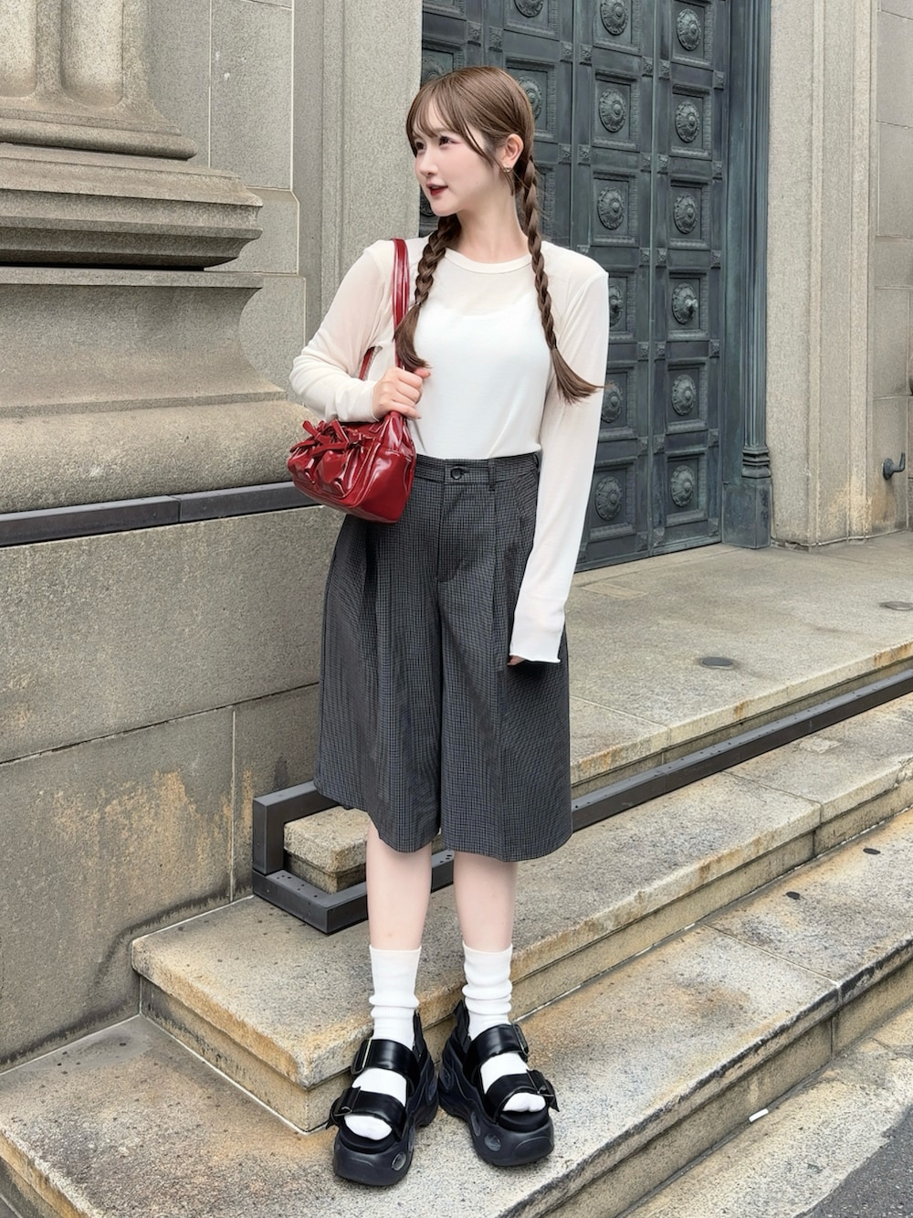 ブラック系のサンダル、レッド系のバッグ、グレー系のパンツを着用したレディースの秋コーディネートの2枚目の写真