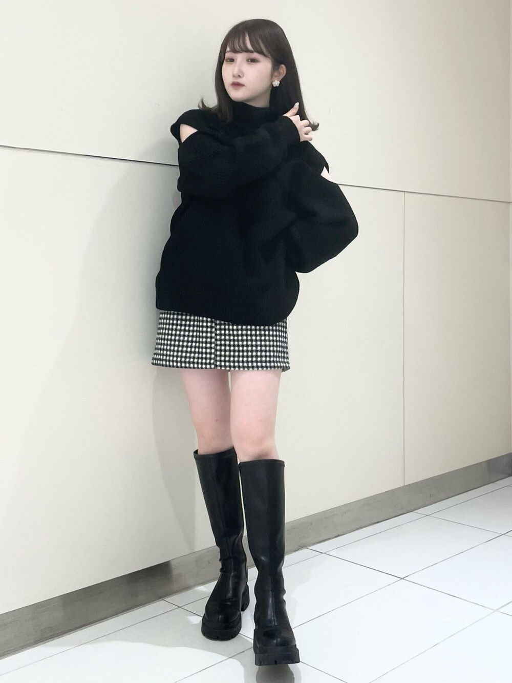 ブラック系のスカート、ブラック系のブーツ、ブラック系のニット/セーターを着用したレディースの秋コーディネートの4枚目の写真