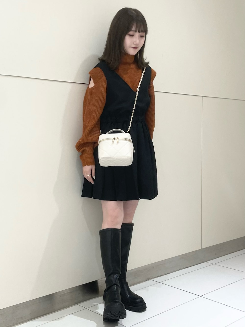 ブラック系のブーツ、ブラック系のワンピース、オレンジ系のニット/セーターを着用したレディースの秋コーディネートの3枚目の写真