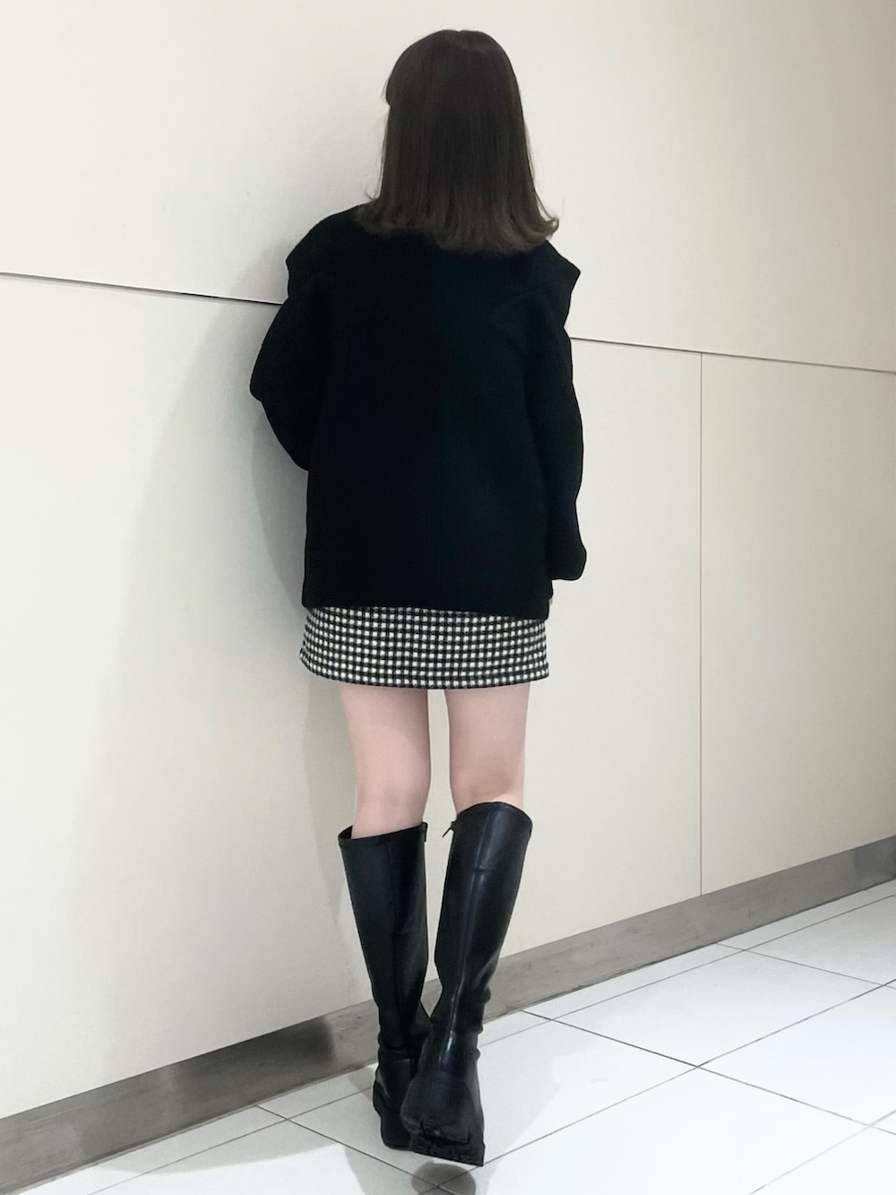 ブラック系のスカート、ブラック系のブーツ、ブラック系のニット/セーターを着用したレディースの秋コーディネートの2枚目の写真