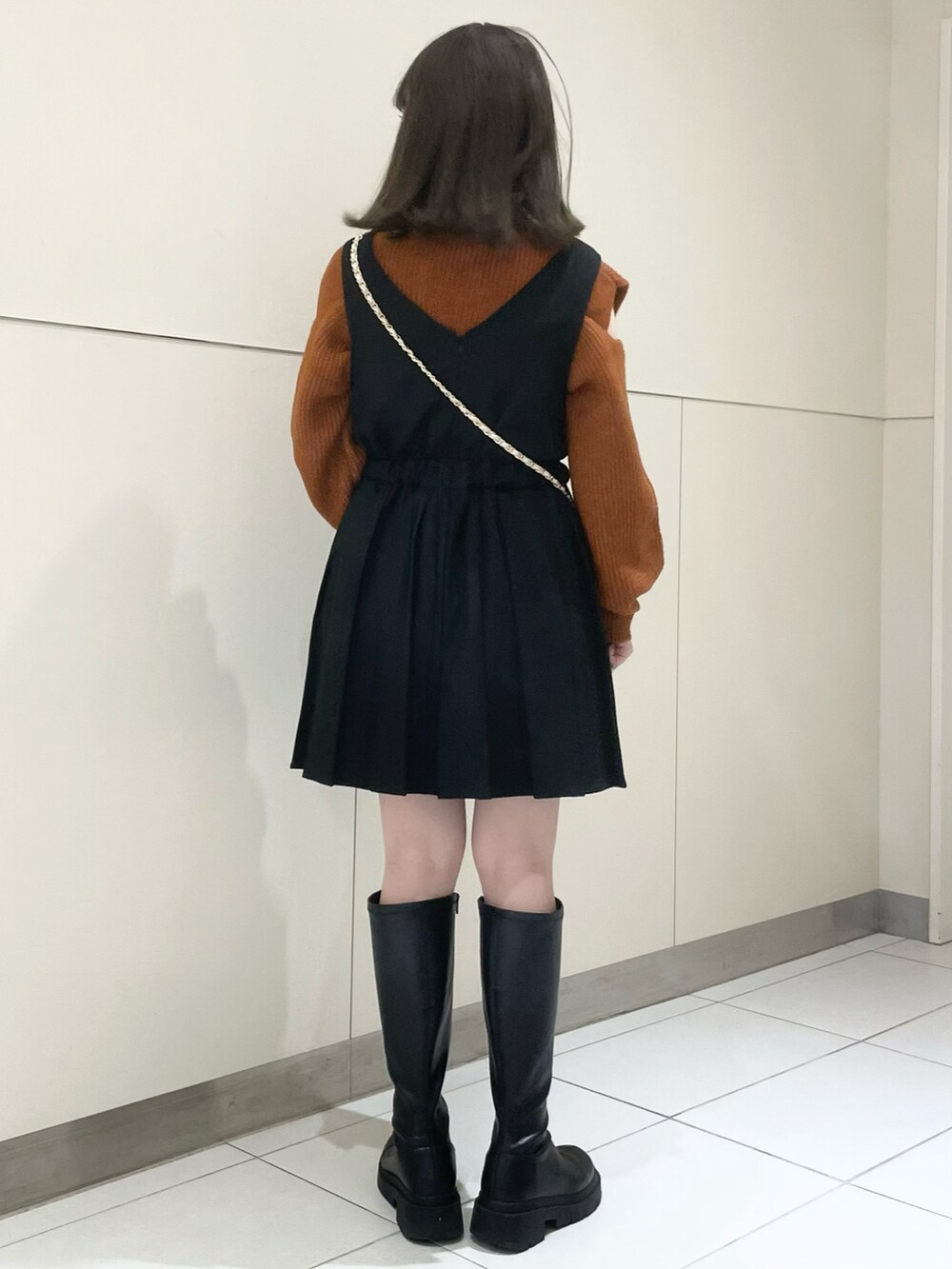 ブラック系のブーツ、ブラック系のワンピース、オレンジ系のニット/セーターを着用したレディースの秋コーディネートの2枚目の写真