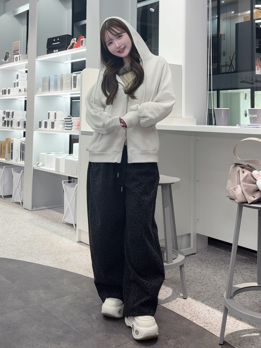 ピンク系のショルダーバッグ、ホワイト系のスニーカー、ホワイト系のパーカーを着用したレディースの冬コーディネートの2枚目の写真