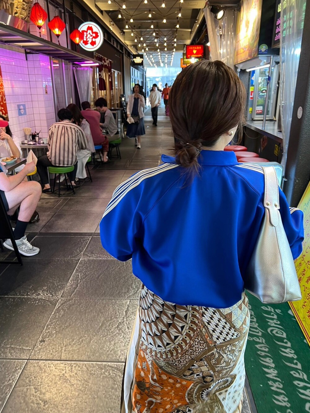 ブルー系のブルゾン、ベージュ系のシューズ、シルバー系のハンドバッグを着用したレディースの秋コーディネートの2枚目の写真