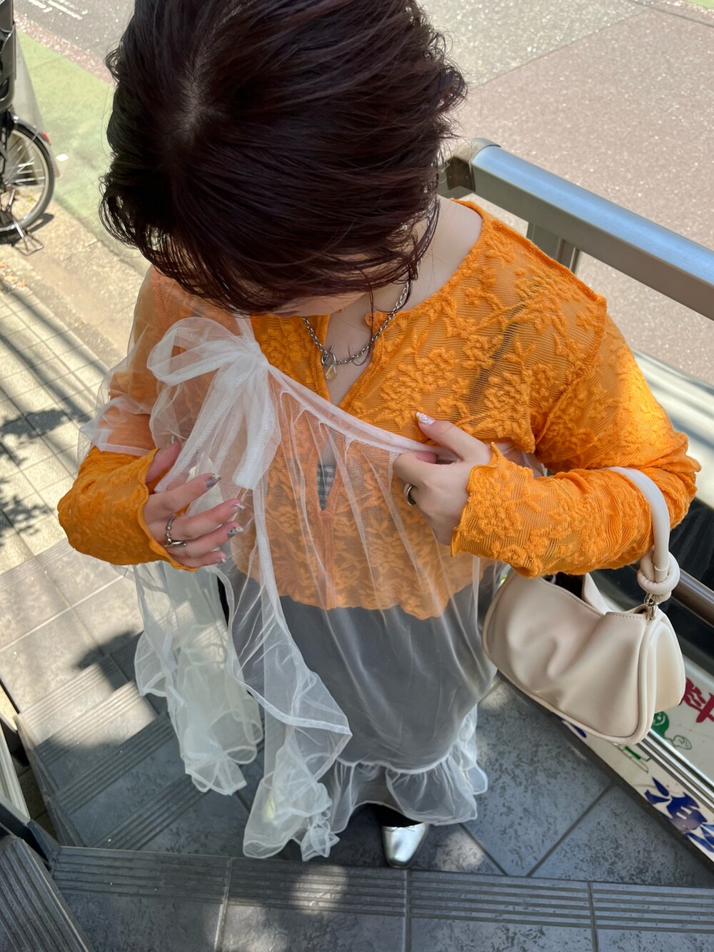 ホワイト系のスカート、オレンジ系のTシャツ/カットソー、ブラック系のパンツを着用したレディースの夏コーディネートの2枚目の写真