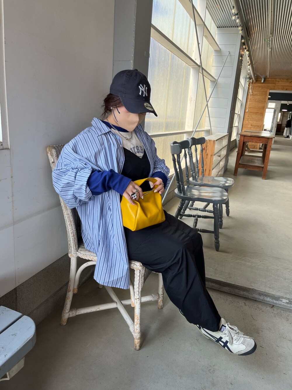 ブラック系のワンピース、グリーン系のハンドバッグ、ホワイト系のスニーカーを着用したレディースの夏コーディネートの2枚目の写真