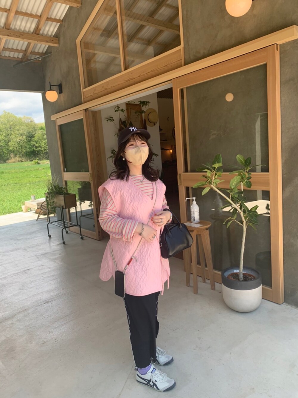 ホワイト系のスニーカー、ブラック系のボストンバッグ、ピンク系のベストを着用したレディースの夏コーディネートの2枚目の写真