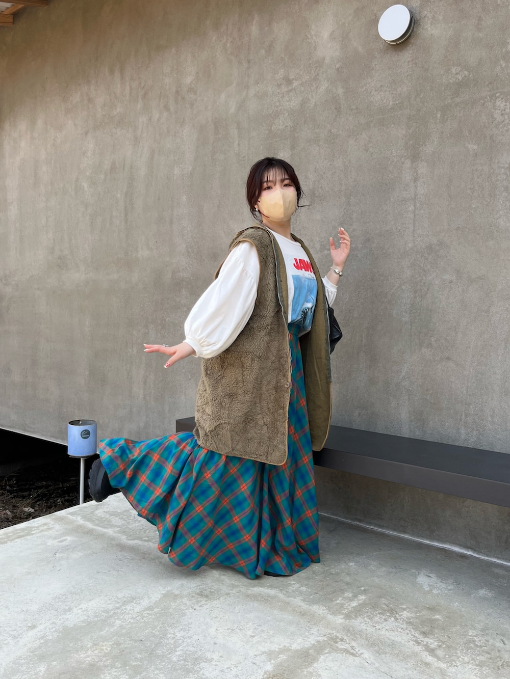 ブラック系のボストンバッグ、グリーン系のベスト、ブルー系のスカートを着用したレディースの夏コーディネートの2枚目の写真