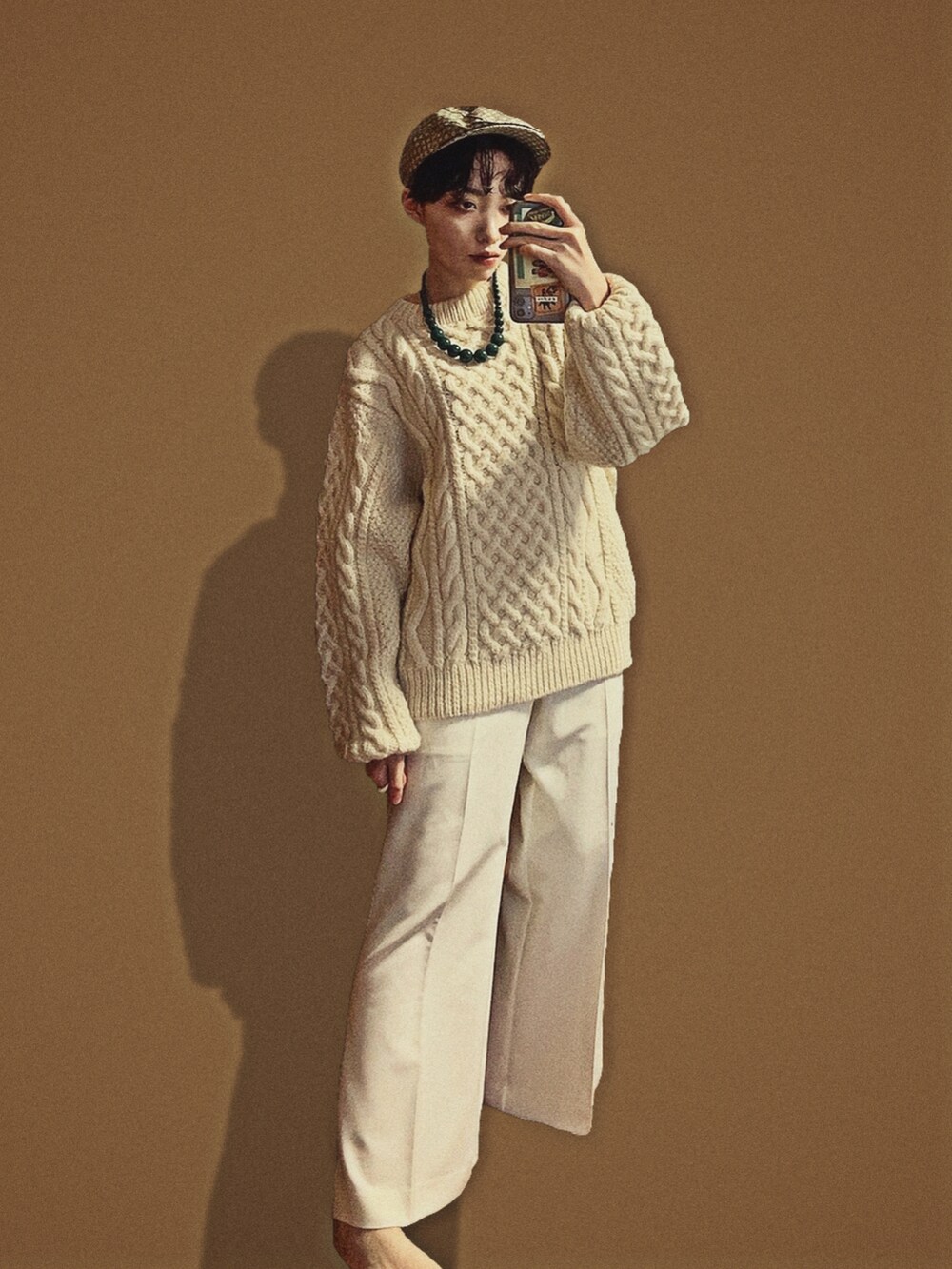 ホワイト系のその他パンツ、ホワイト系のニット/セーター、グリーン系のハンチング/ベレー帽を着用したレディースの冬コーディネートの2枚目の写真