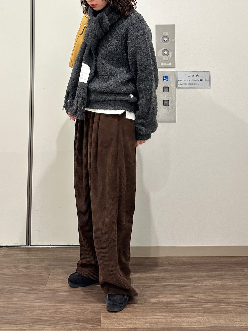 ブラウン系のその他パンツ、イエロー系のハンドバッグ、グレー系のニット/セーターを着用したレディースの冬コーディネートの2枚目の写真