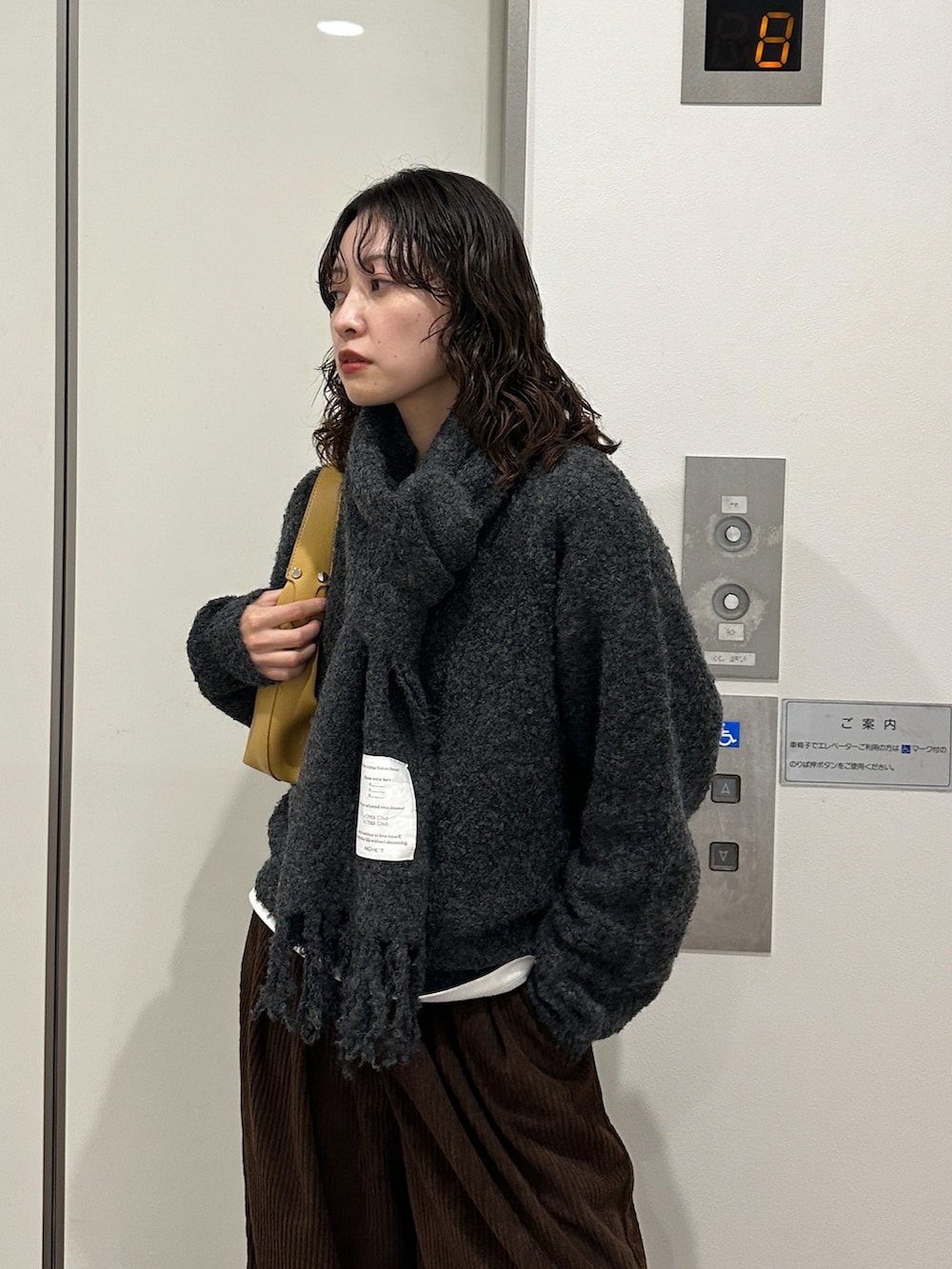 ブラウン系のその他パンツ、イエロー系のハンドバッグ、グレー系のニット/セーターを着用したレディースの冬コーディネートの3枚目の写真