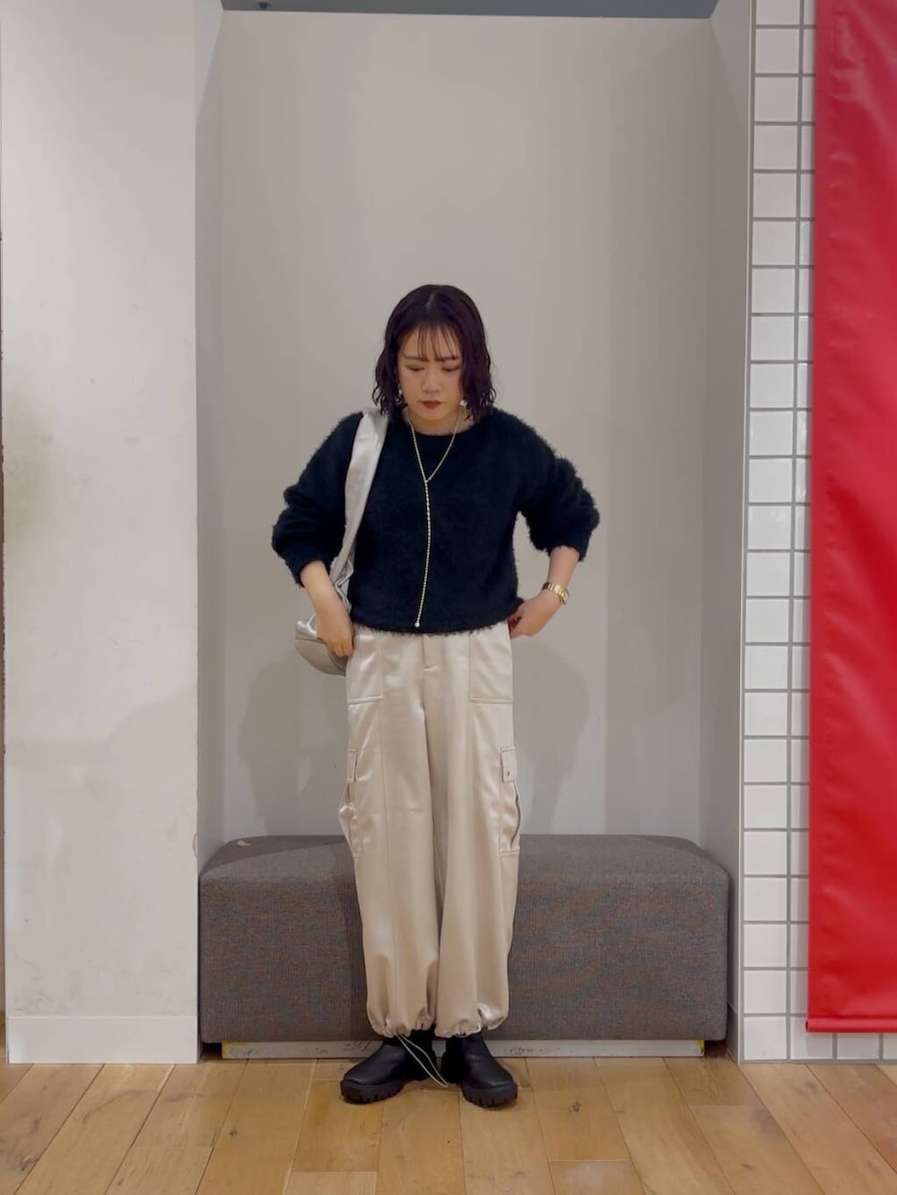 シルバー系のハンドバッグ、ブラック系のブーツ、ブラック系のニット/セーターを着用したレディースの冬コーディネートの3枚目の写真