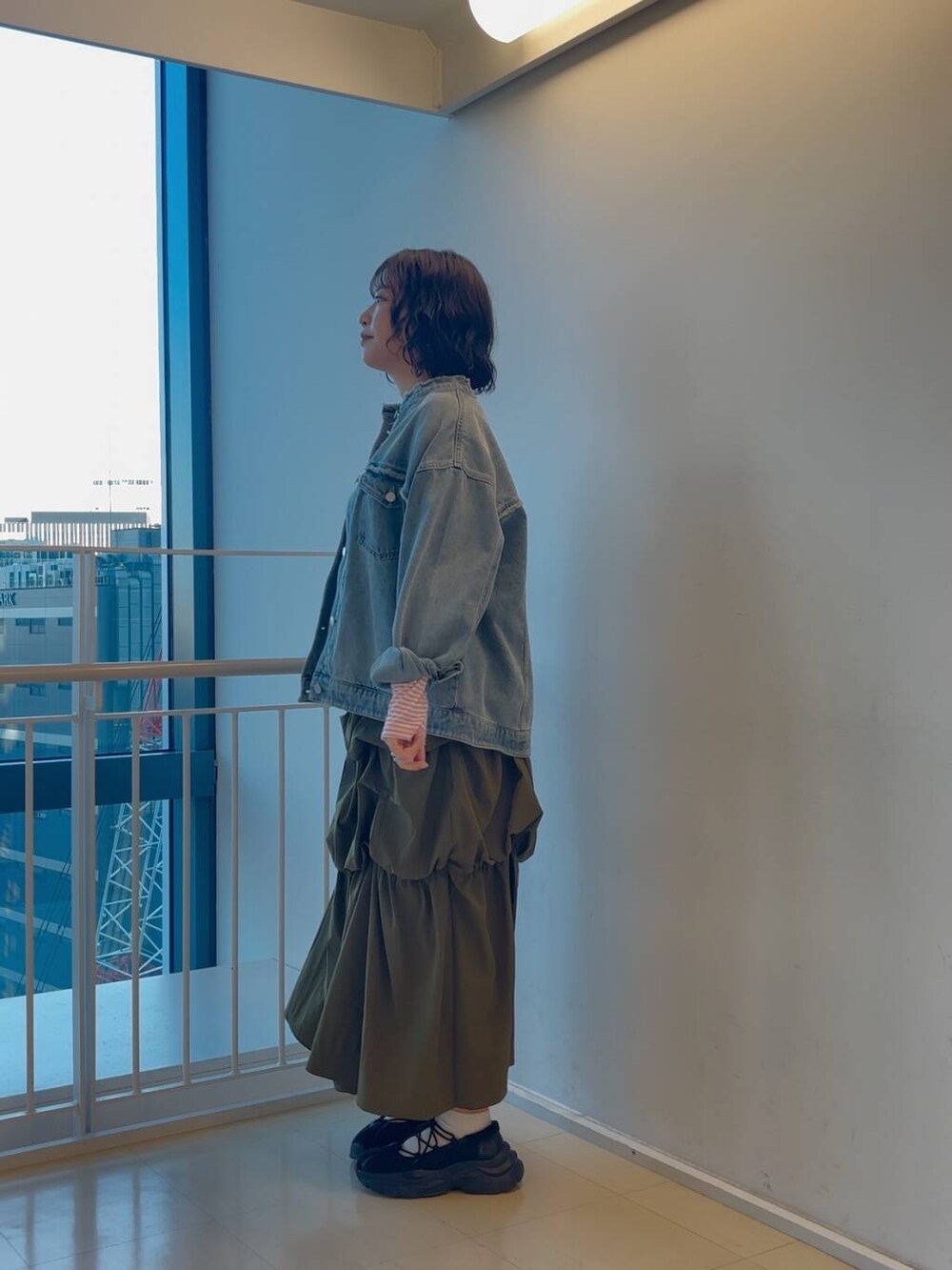 ブラック系のスニーカー、グリーン系のスカート、ピンク系のTシャツ/カットソーを着用したレディースの冬コーディネートの3枚目の写真